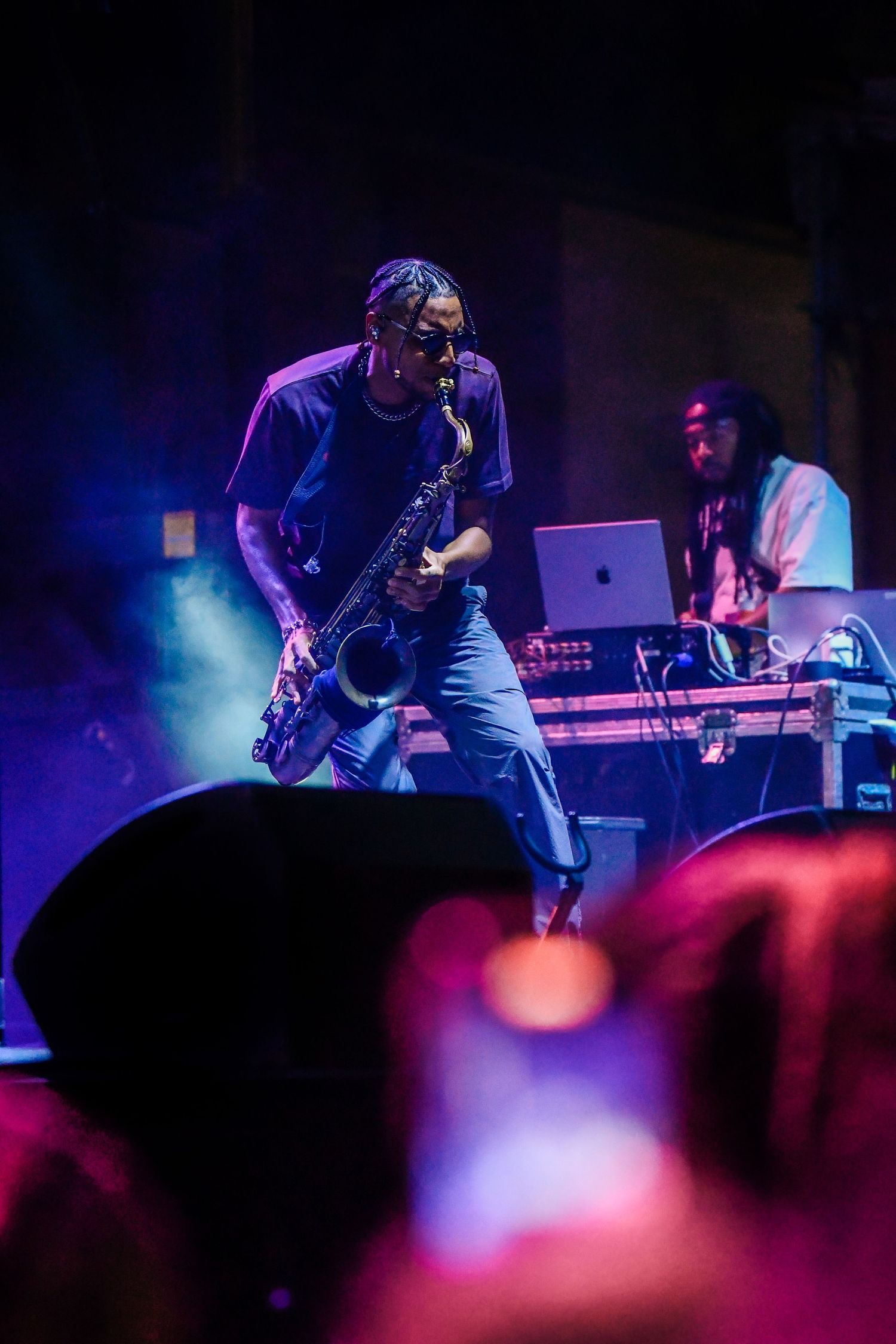 Musicians perform on stage with dramatic purple and blue lighting creating an atmospheric concert environment.