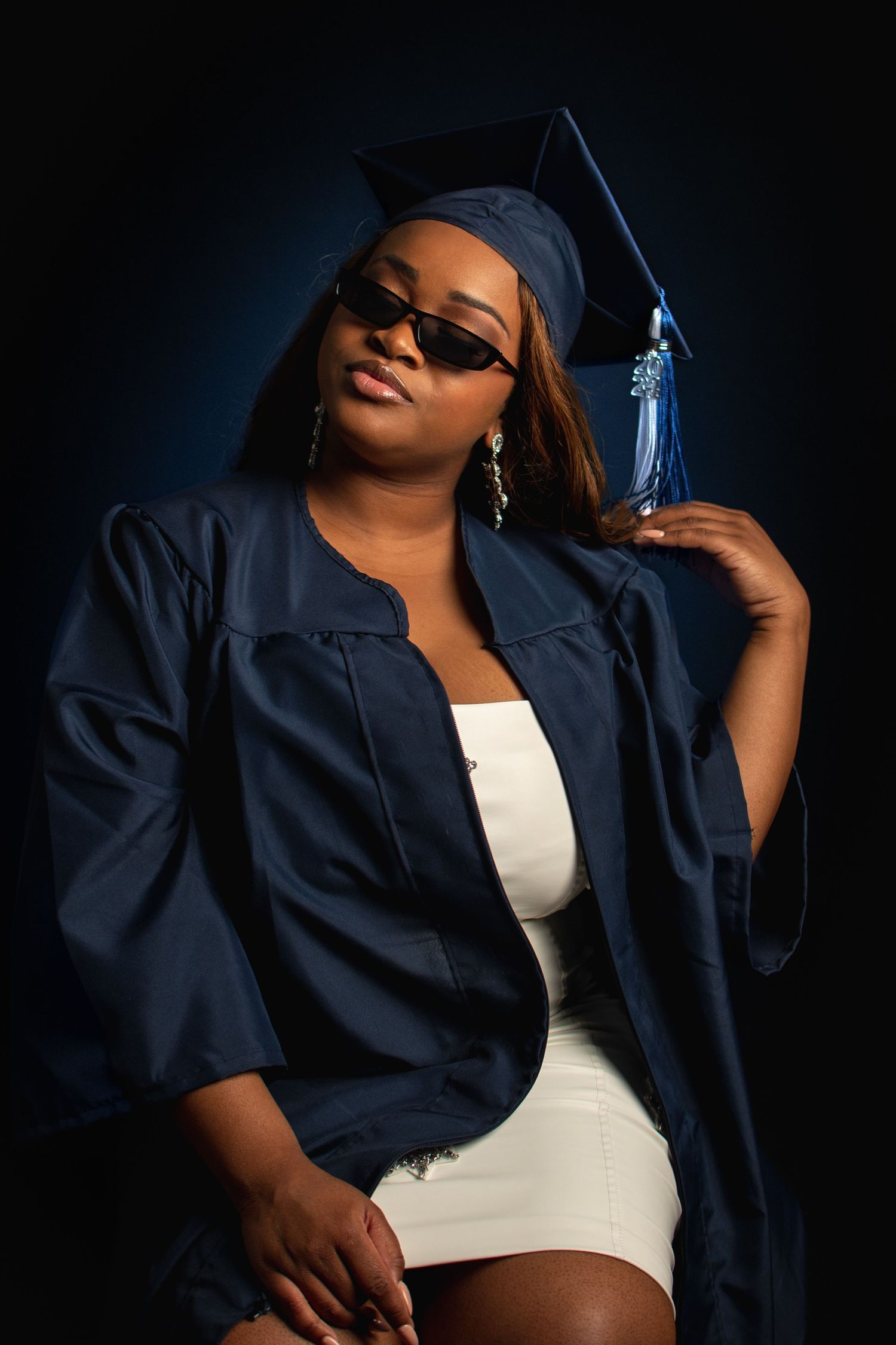 Graduation photo series showing poses in dark blue cap and gown against black background.