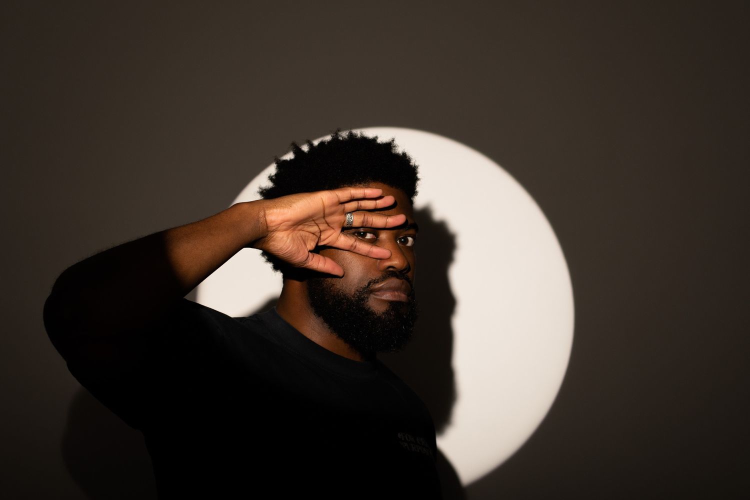 Moody studio portrait with dramatic lighting and circular backdrop element.