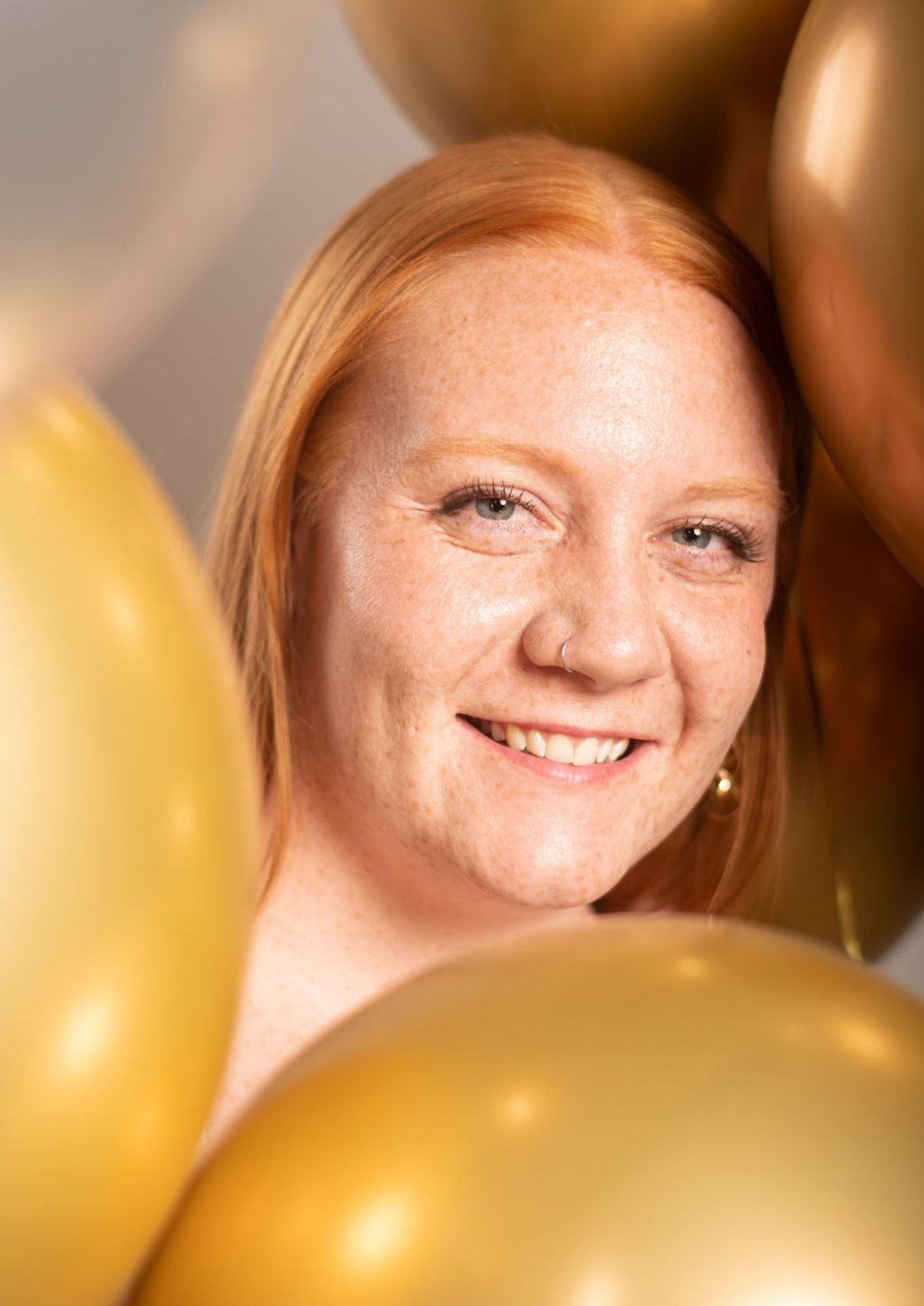 A smiling person with freckles and red hair is photographed with blurred yellow bananas in the foreground.