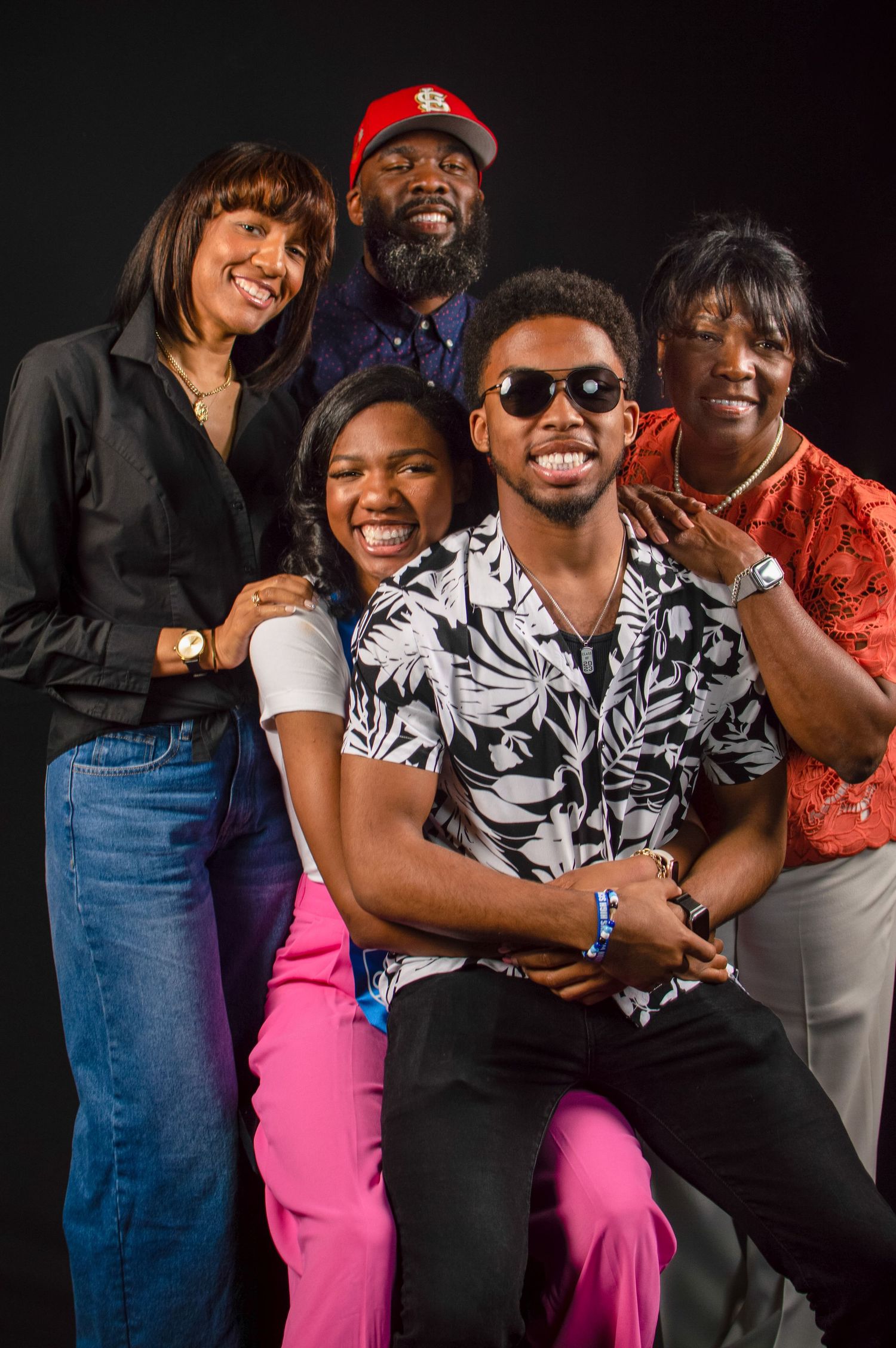 A group of people wearing casual attire pose together and laugh while embracing in a photo series.