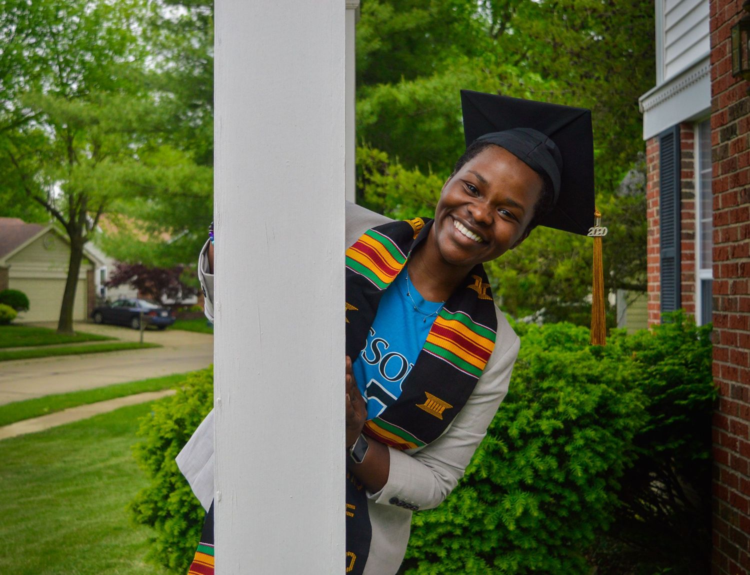 Candid graduation photos between white columns with greenery in background.