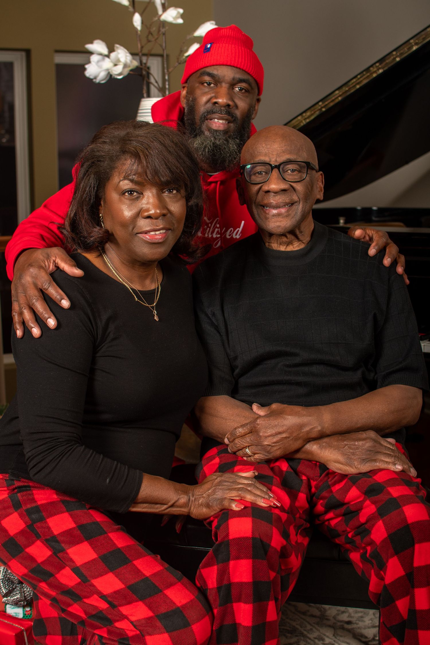 Holiday family photo with couples wearing coordinated red and black buffalo plaid outfits.
