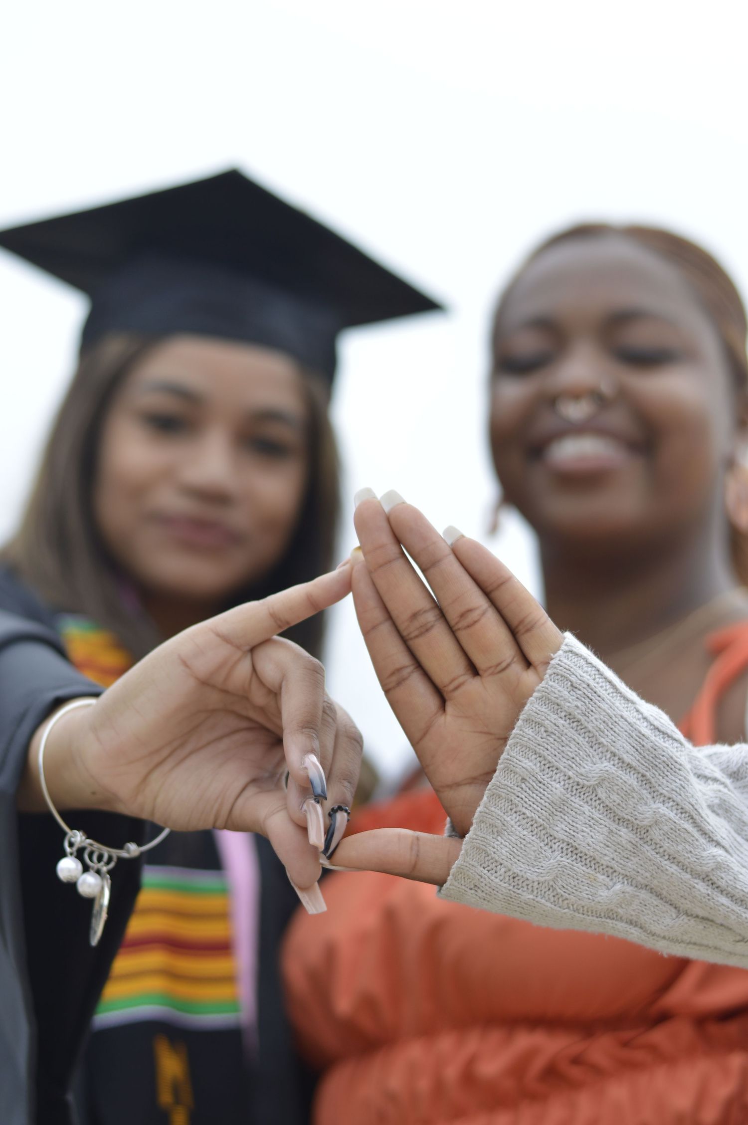 Multiple hands holding diplomas during graduation ceremony.