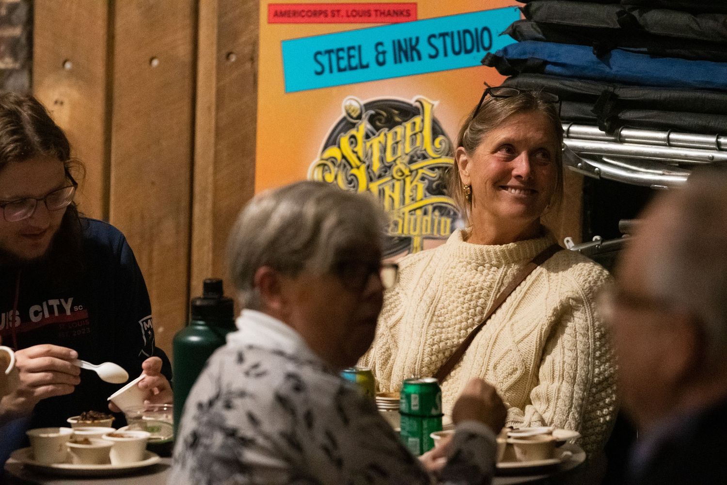 A group of people gather around a table during what appears to be a casual social event or meeting.