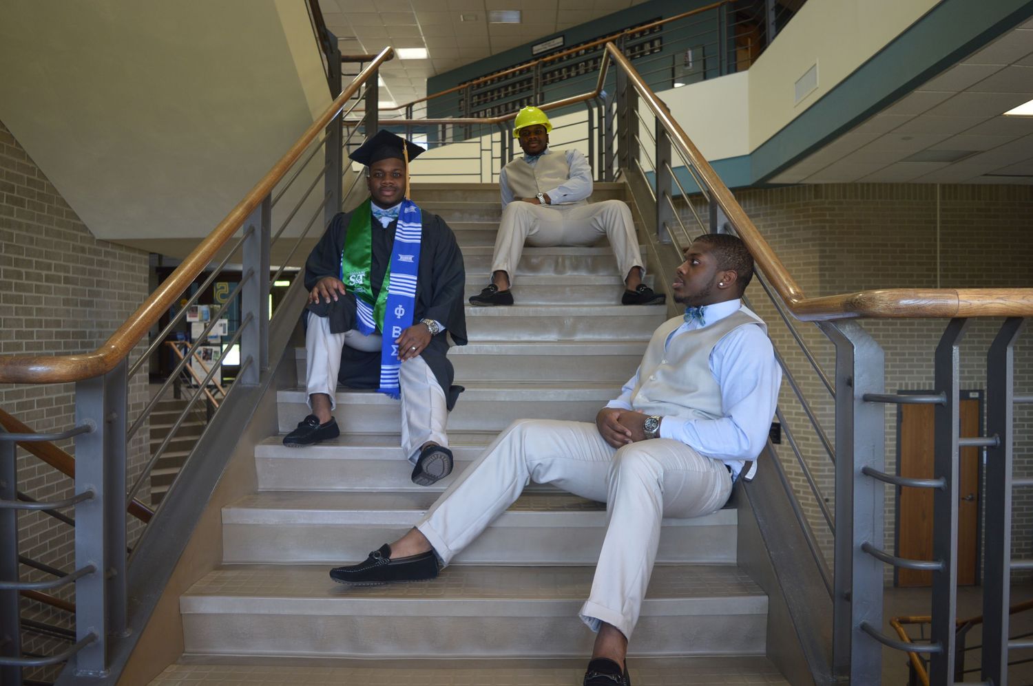 Graduates relaxing on modern staircase during photo session.