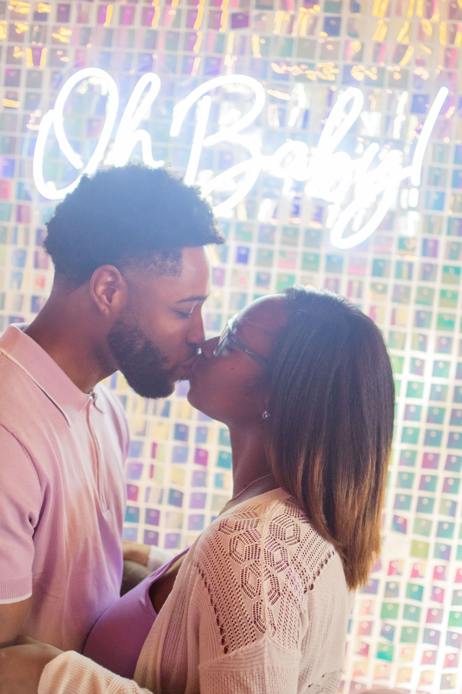 A romantic moment captured against a colorful mosaic wall with soft lighting.