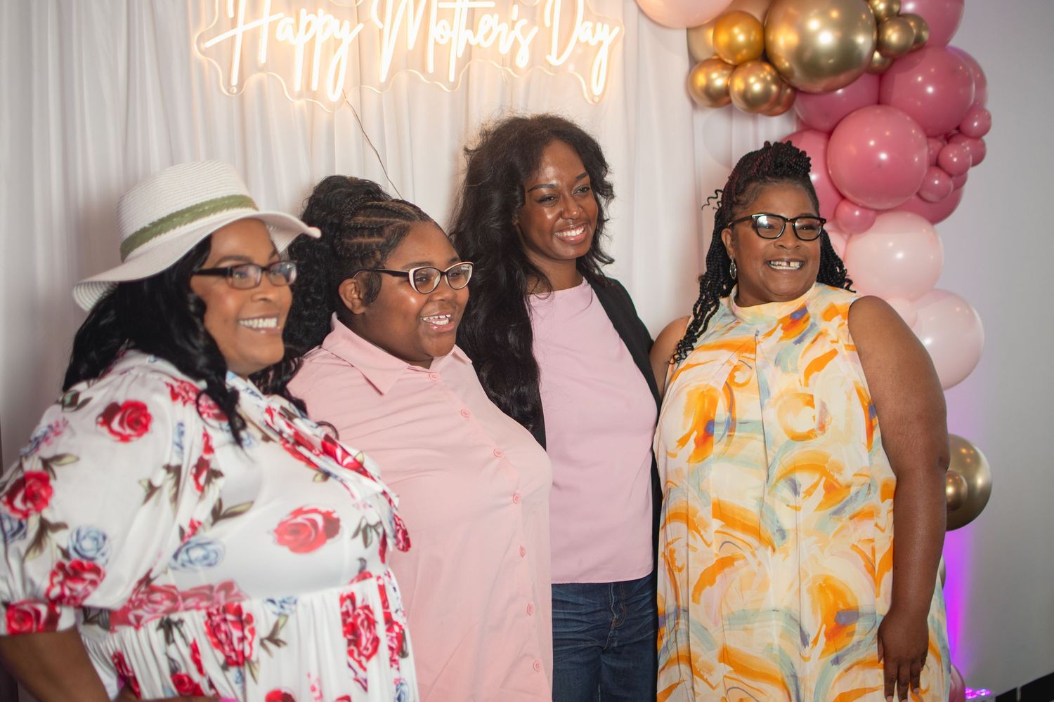 group of black women posing under neon sign with balloons