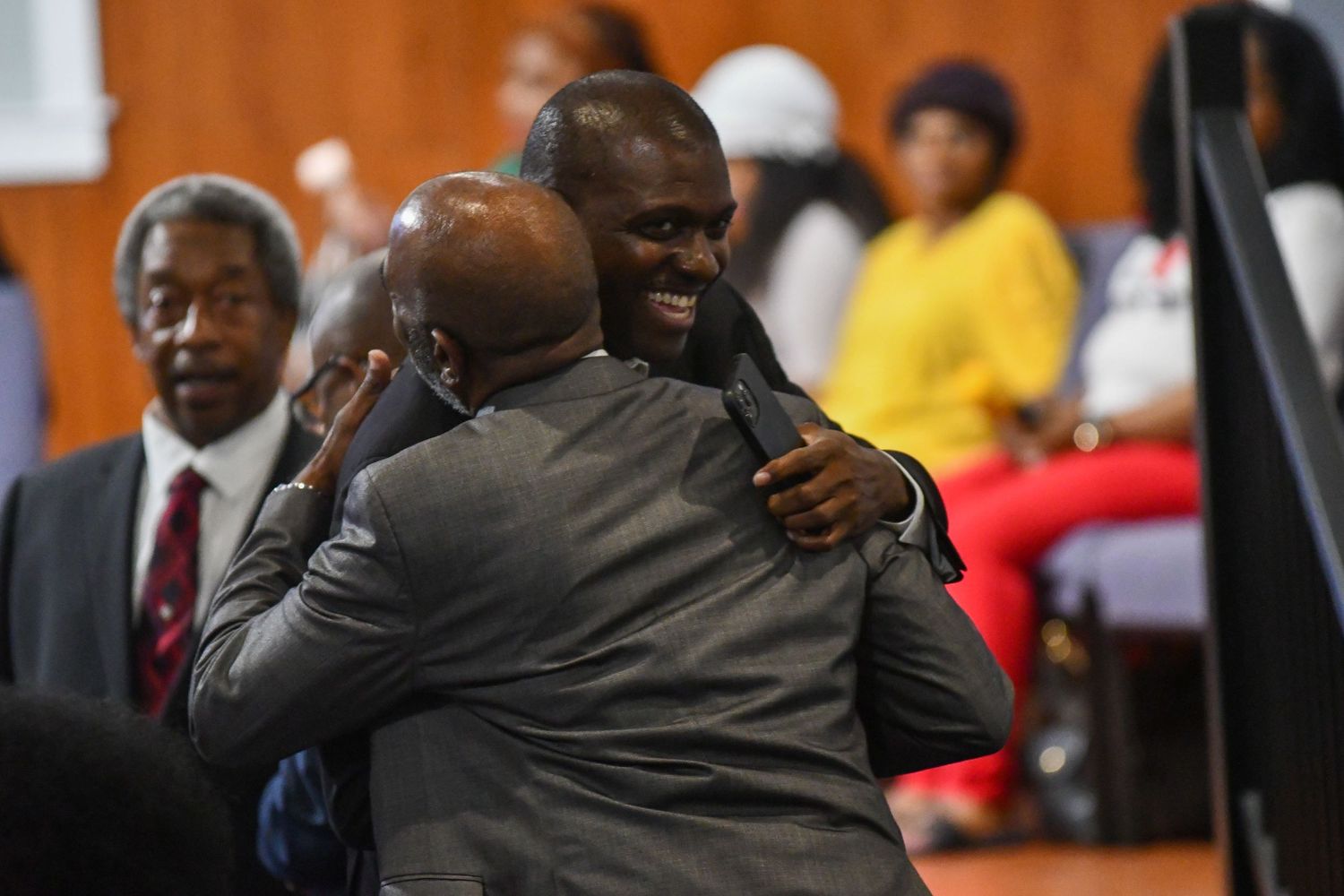Basketball players and coaches embrace in celebration during an emotional moment on the court.