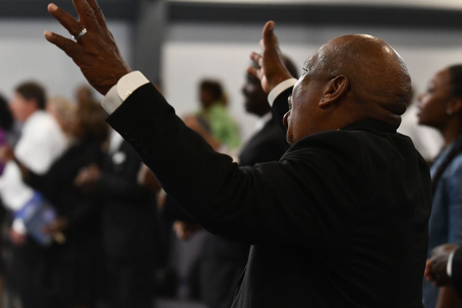 A person raises their hand in a dimly lit room during what appears to be a business or conference event.