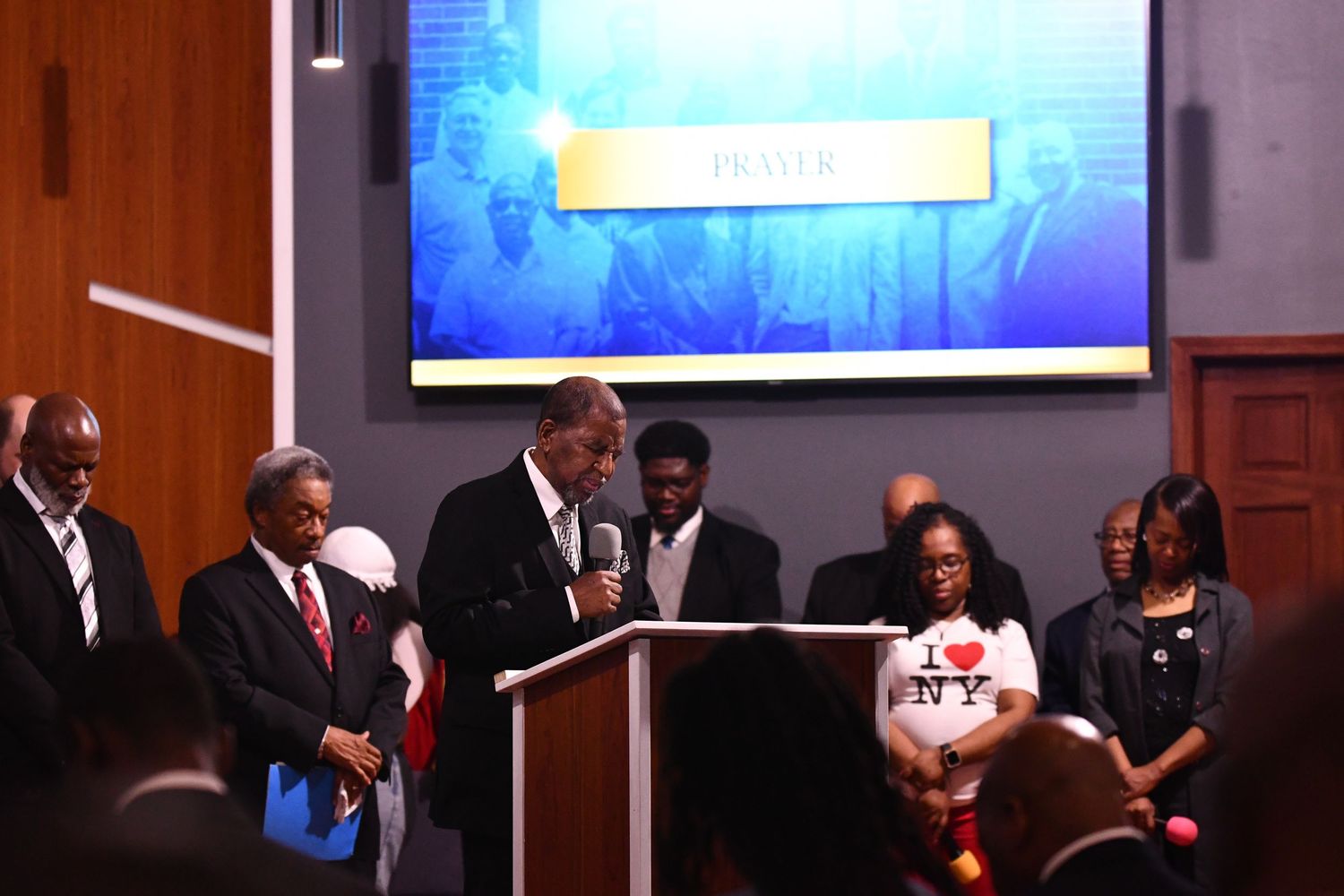 A group of people stand at a podium during what appears to be a formal event or presentation.