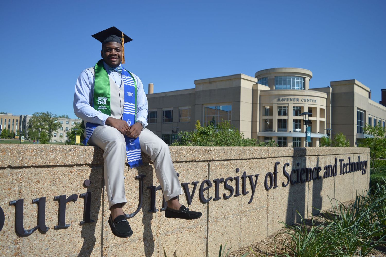 Graduation photos taken outside a university building with stone walls and modern architecture.