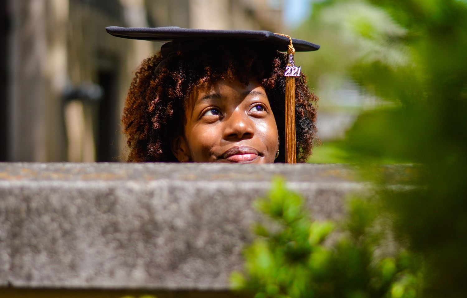 Graduate portrait through stone architectural elements on campus.