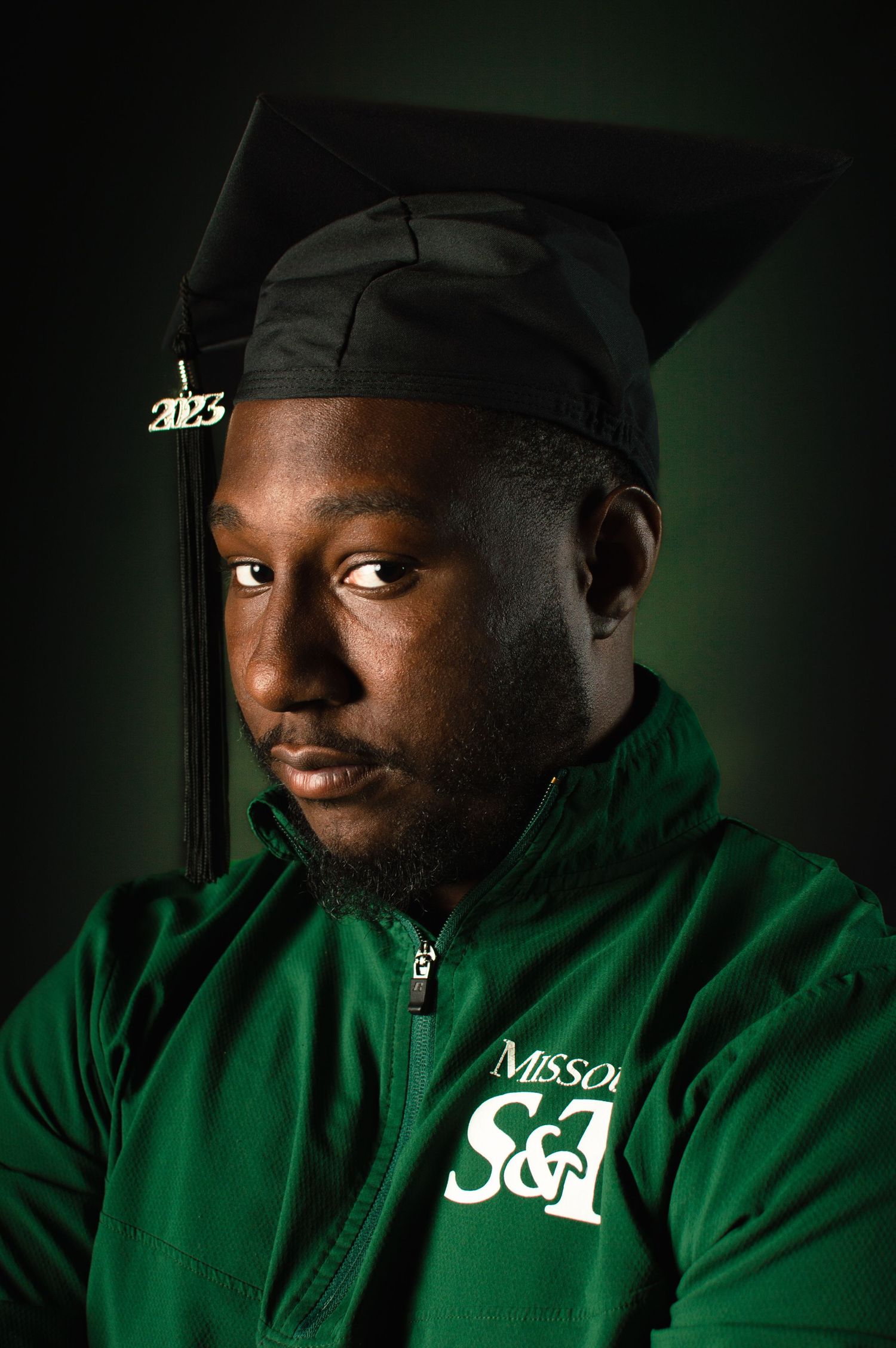 Portrait series of a person wearing a green hoodie with white text against a dark background.