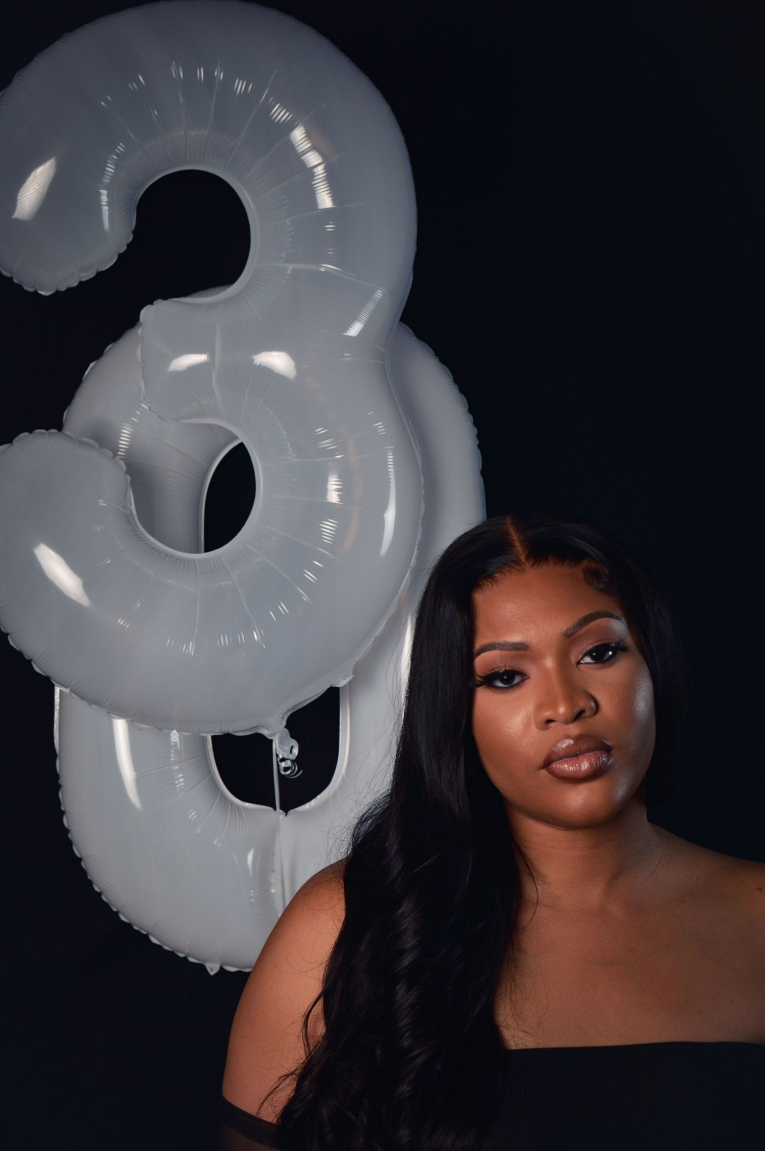 Portrait series with white balloon numbers against dark background creating dramatic contrast and lighting effect.