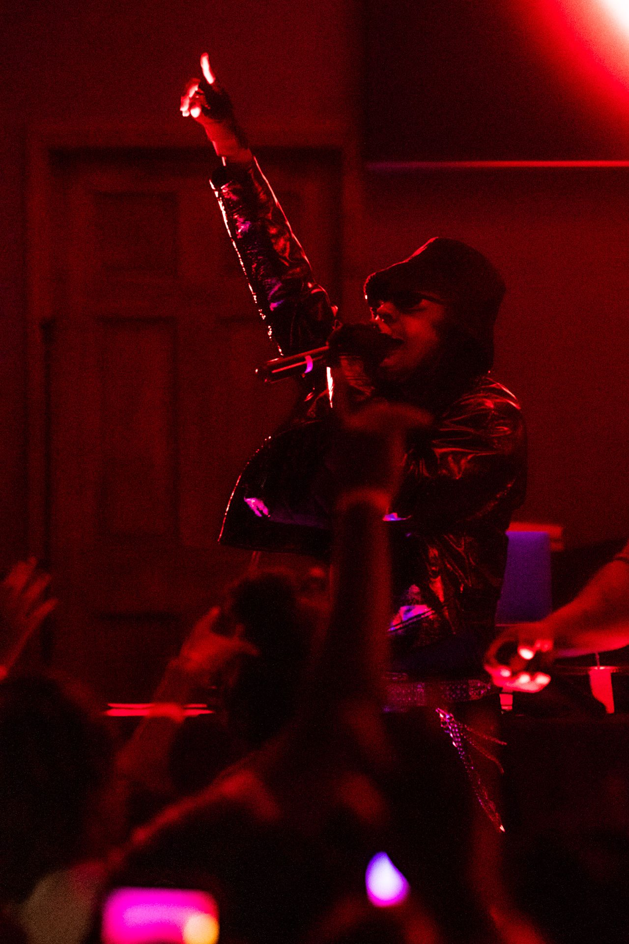 Musicians perform on stage under dramatic red lighting at a concert venue.