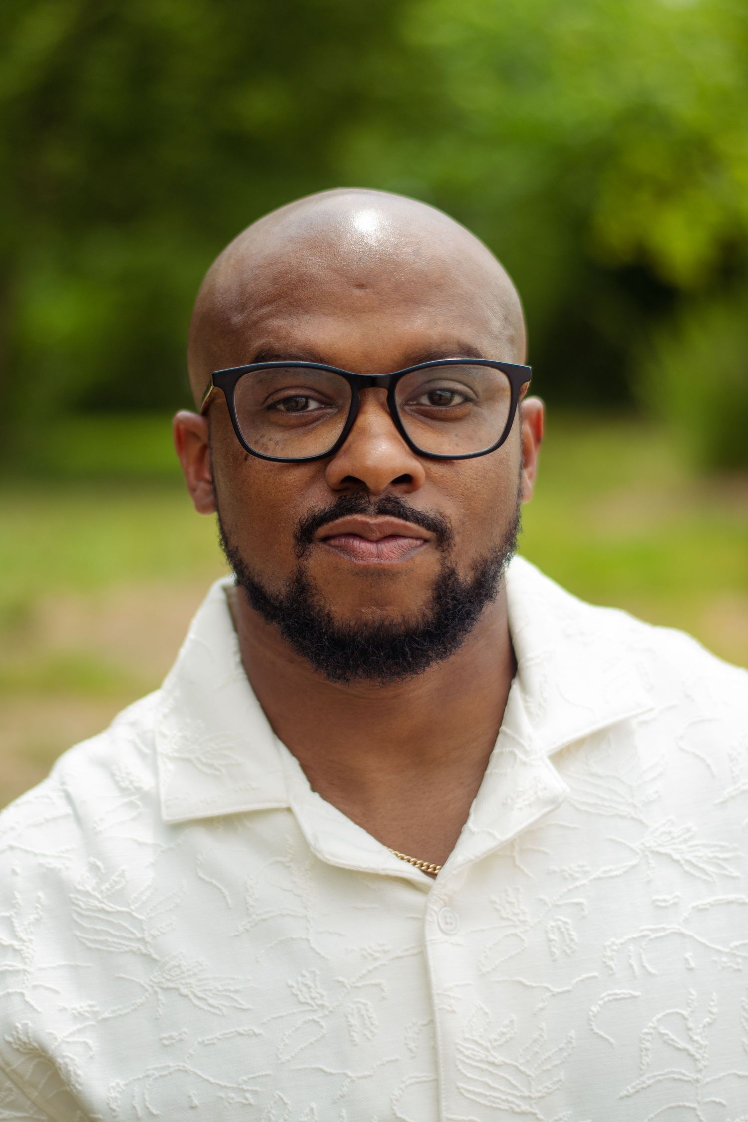 Professional headshot series showing a person in a white textured shirt with glasses and facial hair against a blurred green background.