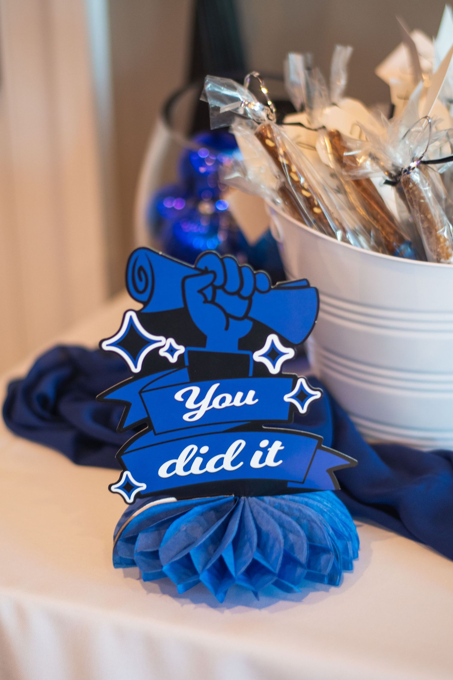 Blue decorative paper rosettes with text and star accents displayed in a row against a light colored background.