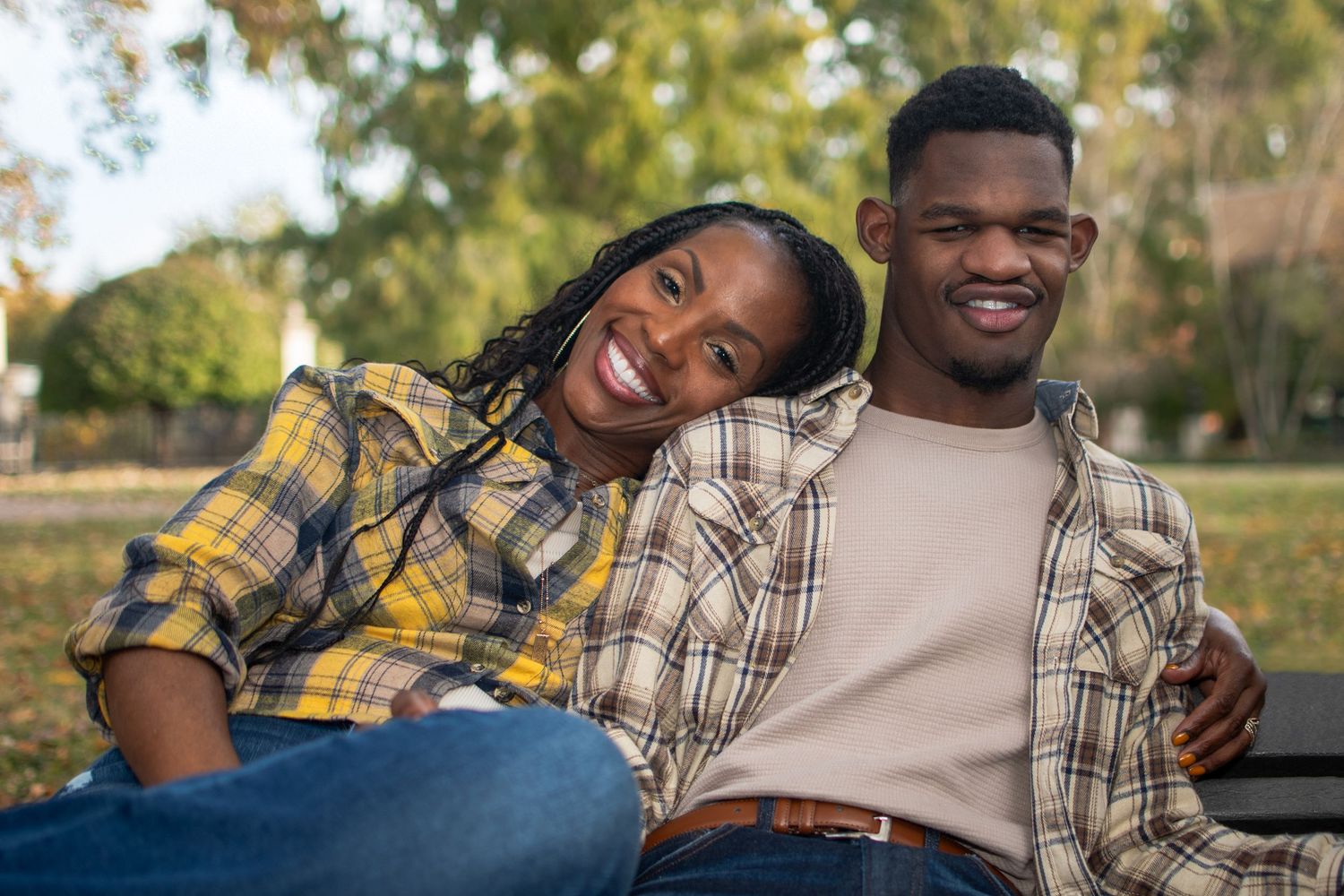 Group sharing laughs while relaxing outdoors in plaid shirts and casual wear.