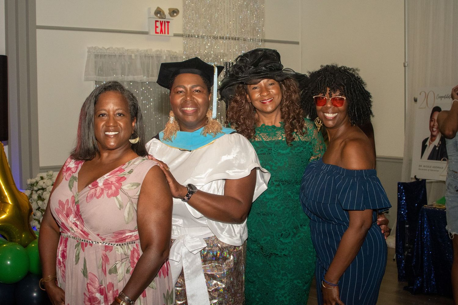 A group of people pose together at a celebration wearing formal attire including pink, white, green and blue dresses.