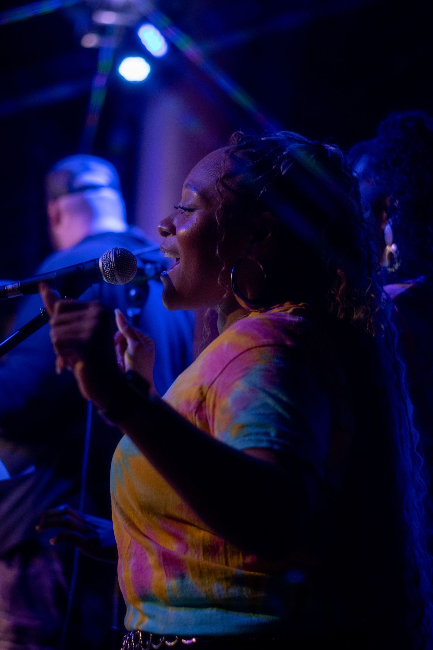 Concert performers singing passionately on stage under dramatic blue lighting at a live music venue.