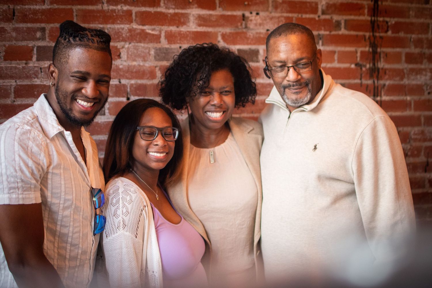 Friends gathered for a group photo against an exposed brick wall at a celebration.