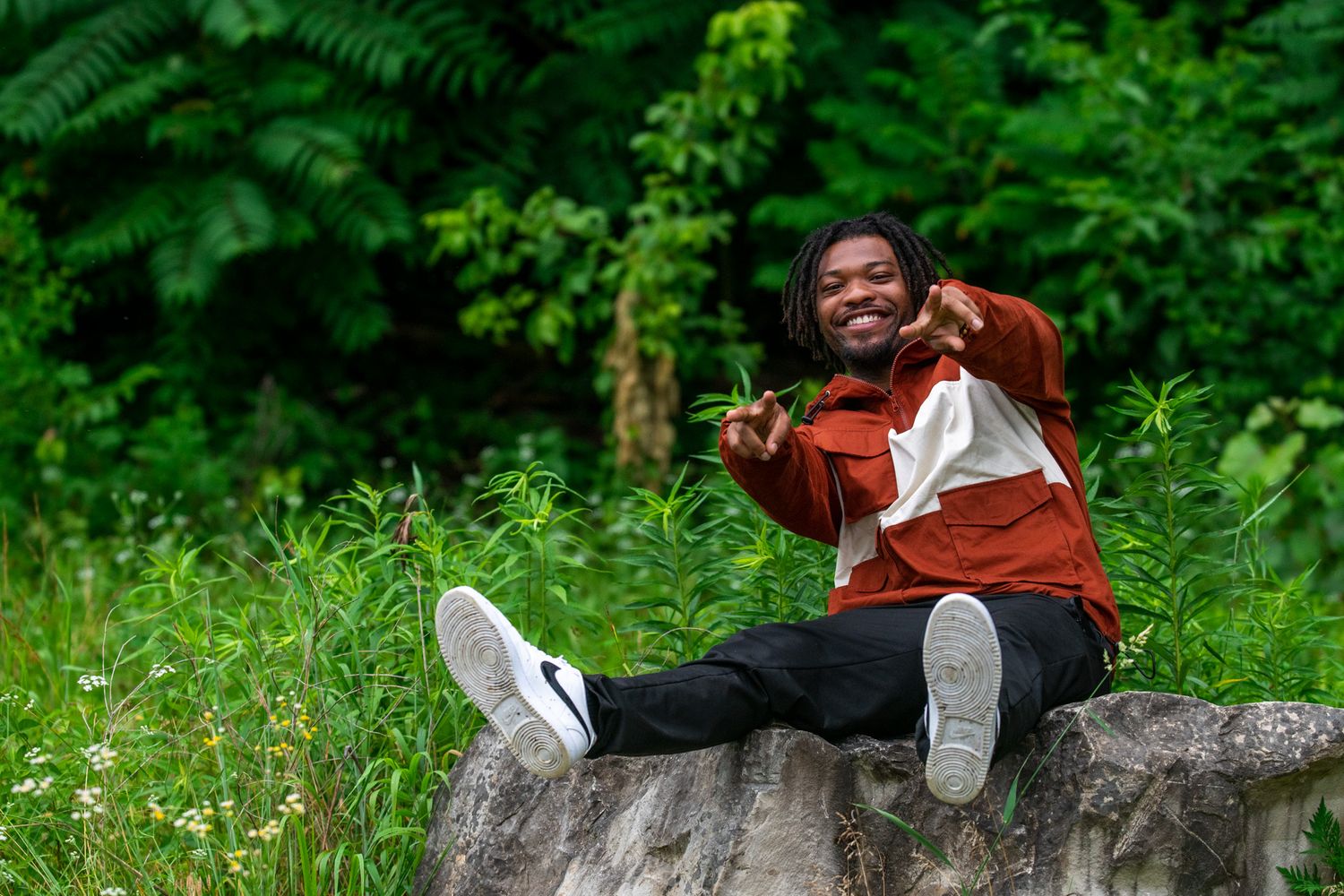 Children play and pose on large fallen tree trunks in a lush green forest setting.