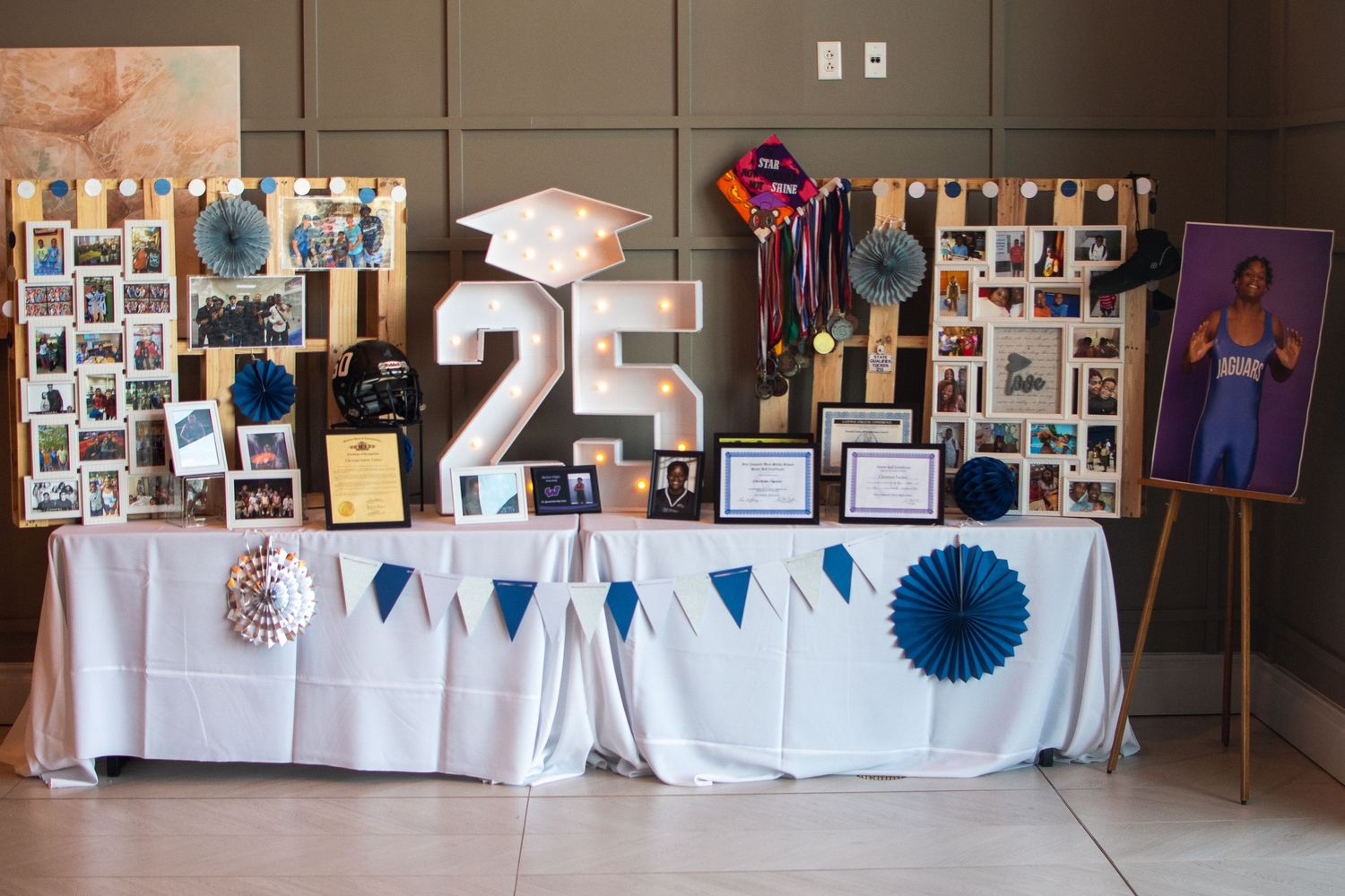 A long table decorated with white linens and photo displays stretches across a banquet hall.