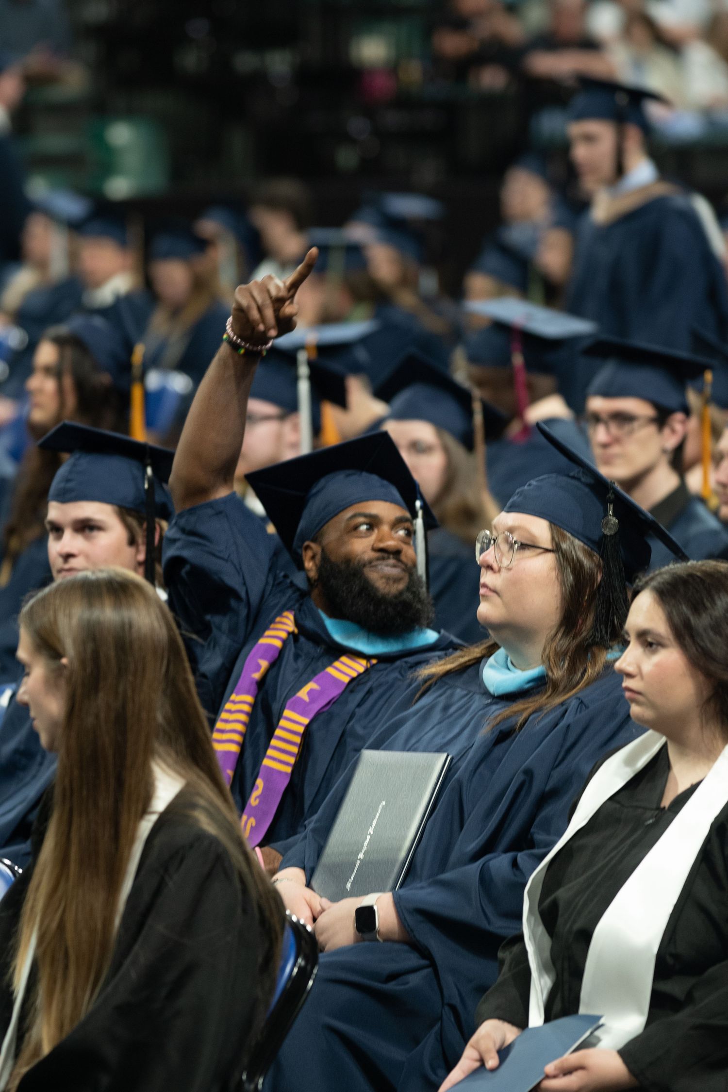 Graduates in blue caps and gowns celebrate during commencement ceremony.