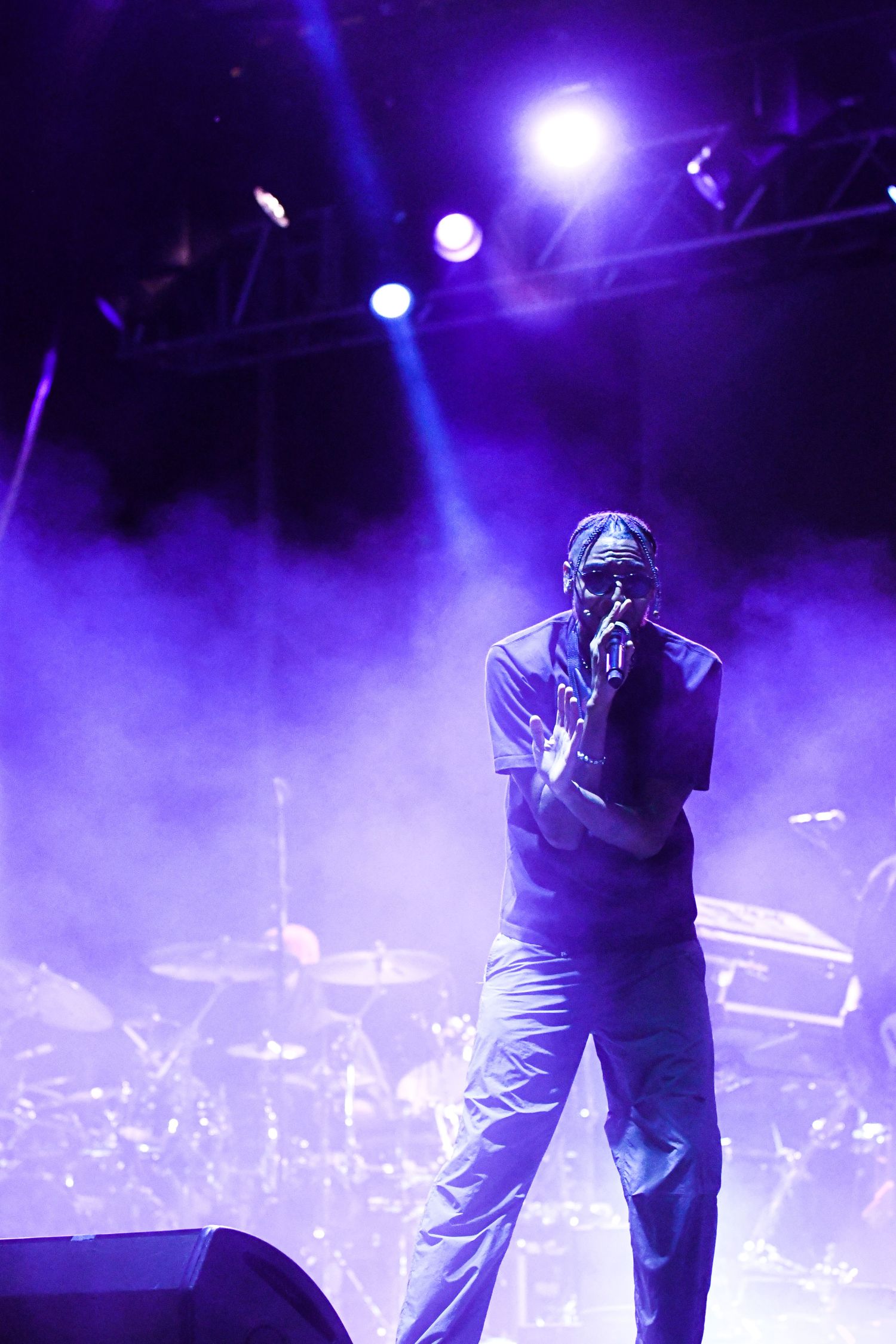 Silhouetted performers on stage with dramatic purple lighting and fog effects create an atmospheric concert scene.