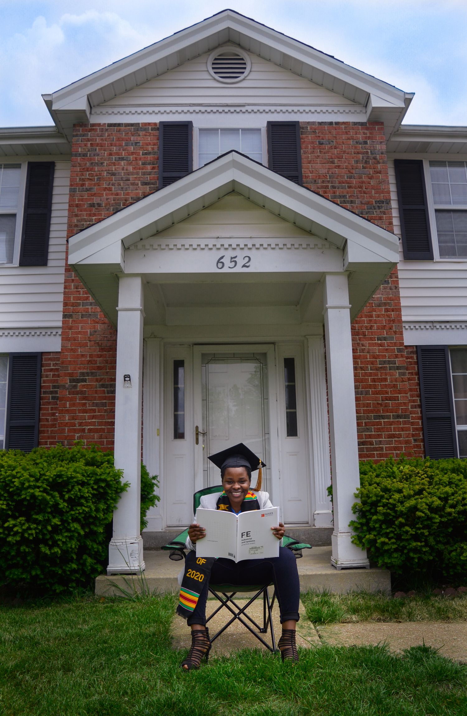 Graduation photo session setup with chair in front of brick building entrance.