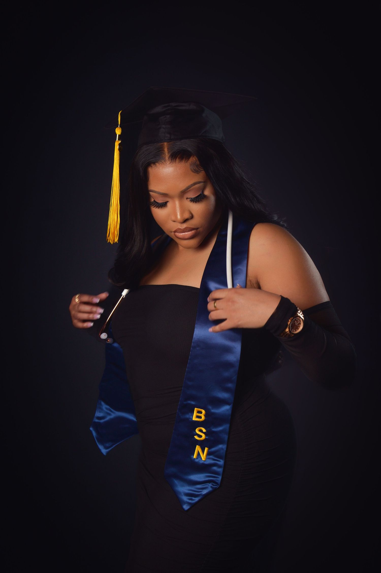 Artistic graduation portraits with blue stole and gold tassel against dark dramatic background.