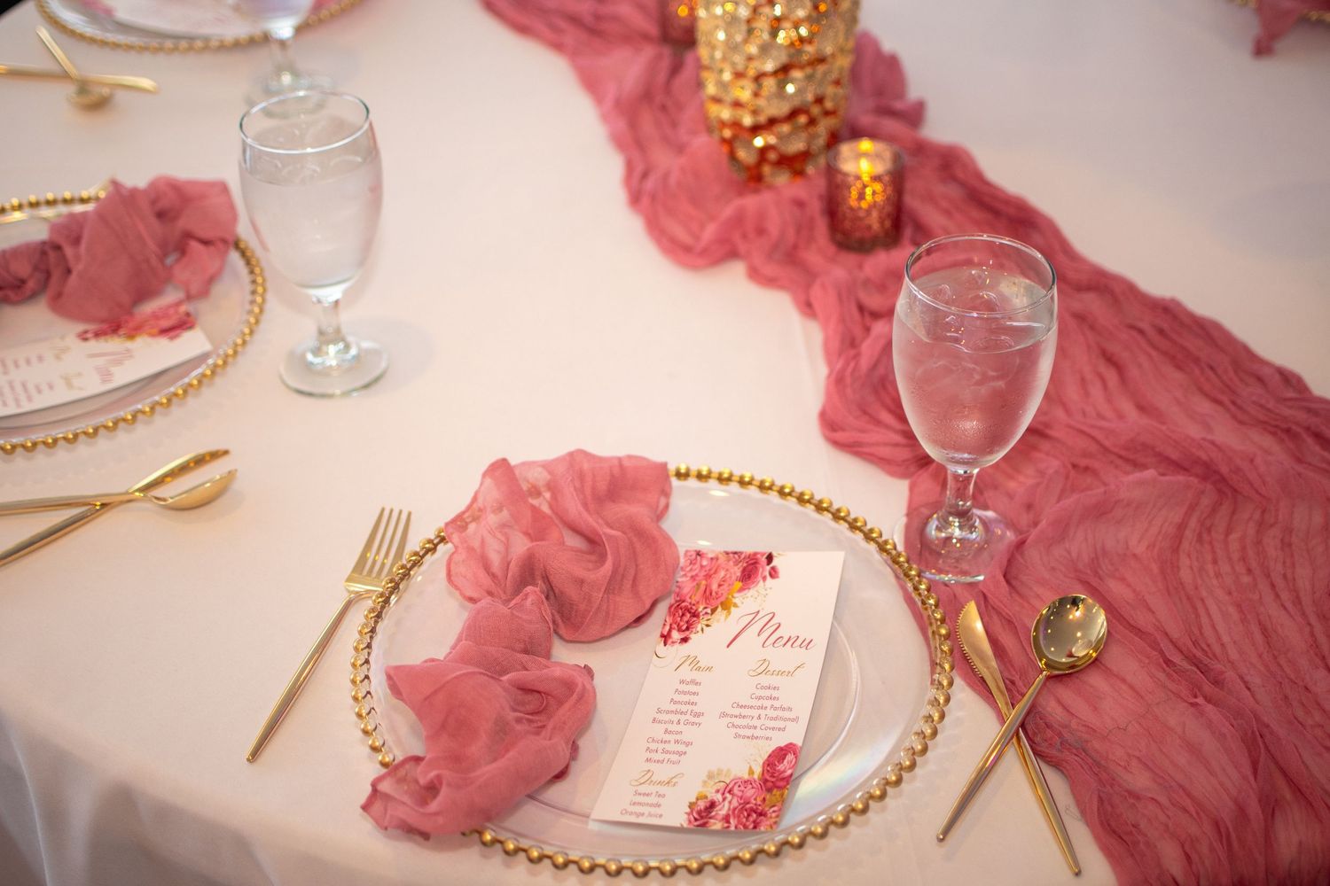 Pink and gold table decorations with glassware at an elegant celebration.