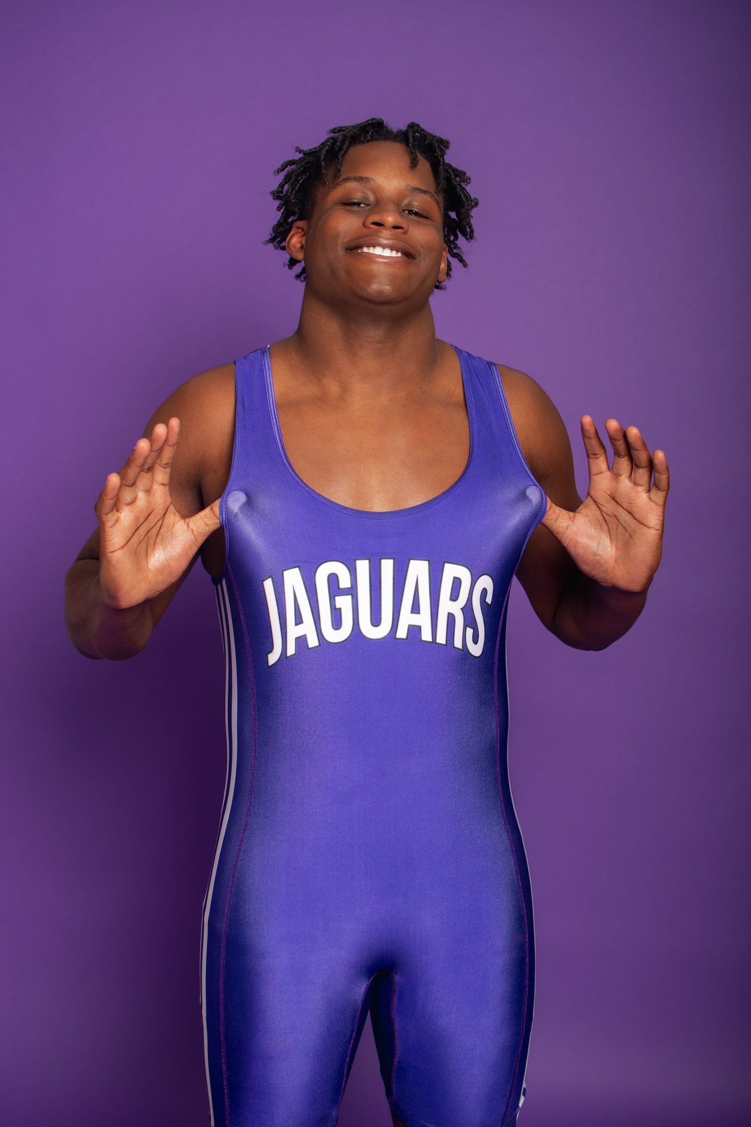 Athlete in blue Jaguars wrestling singlet poses confidently against purple background.