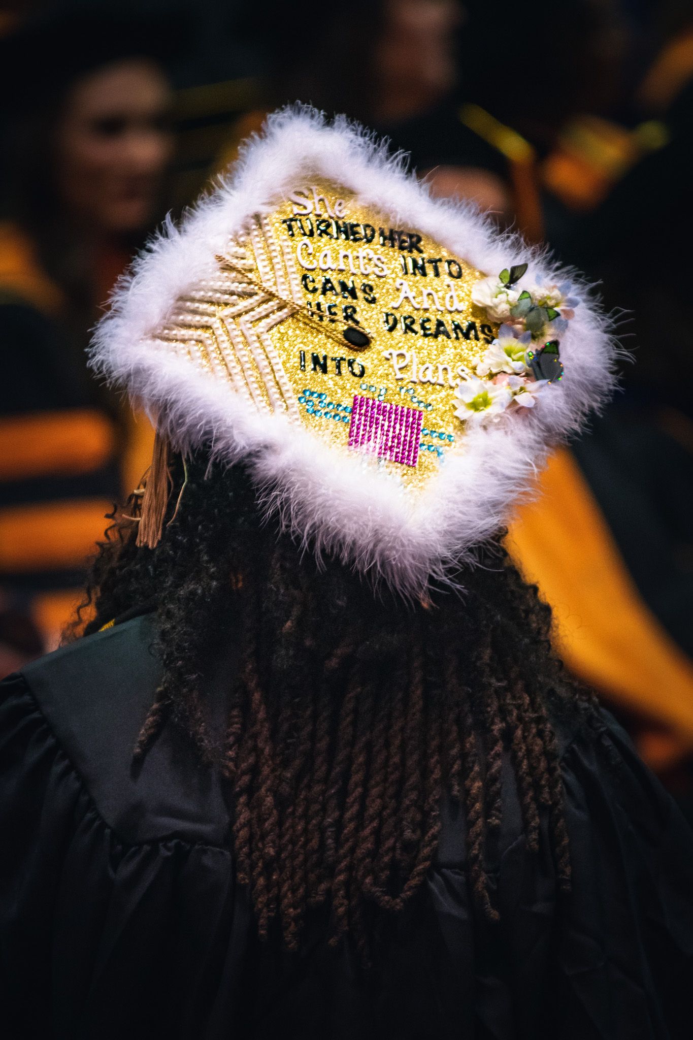 A graduation cap decorated with yellow text and white feather trim shown from different angles in multiple photos.