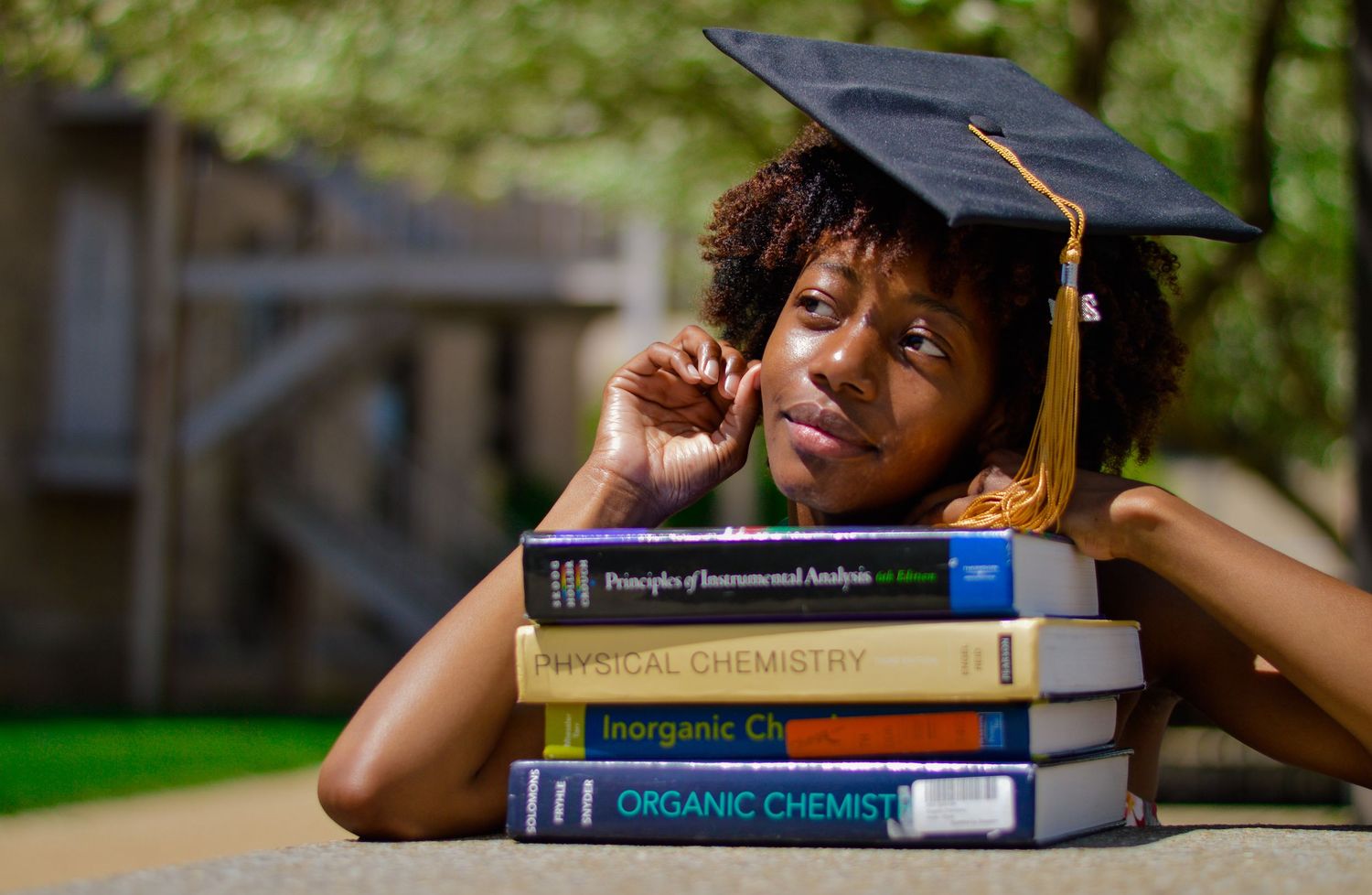Stack of chemistry textbooks with graduation cap symbolizing academic achievement.
