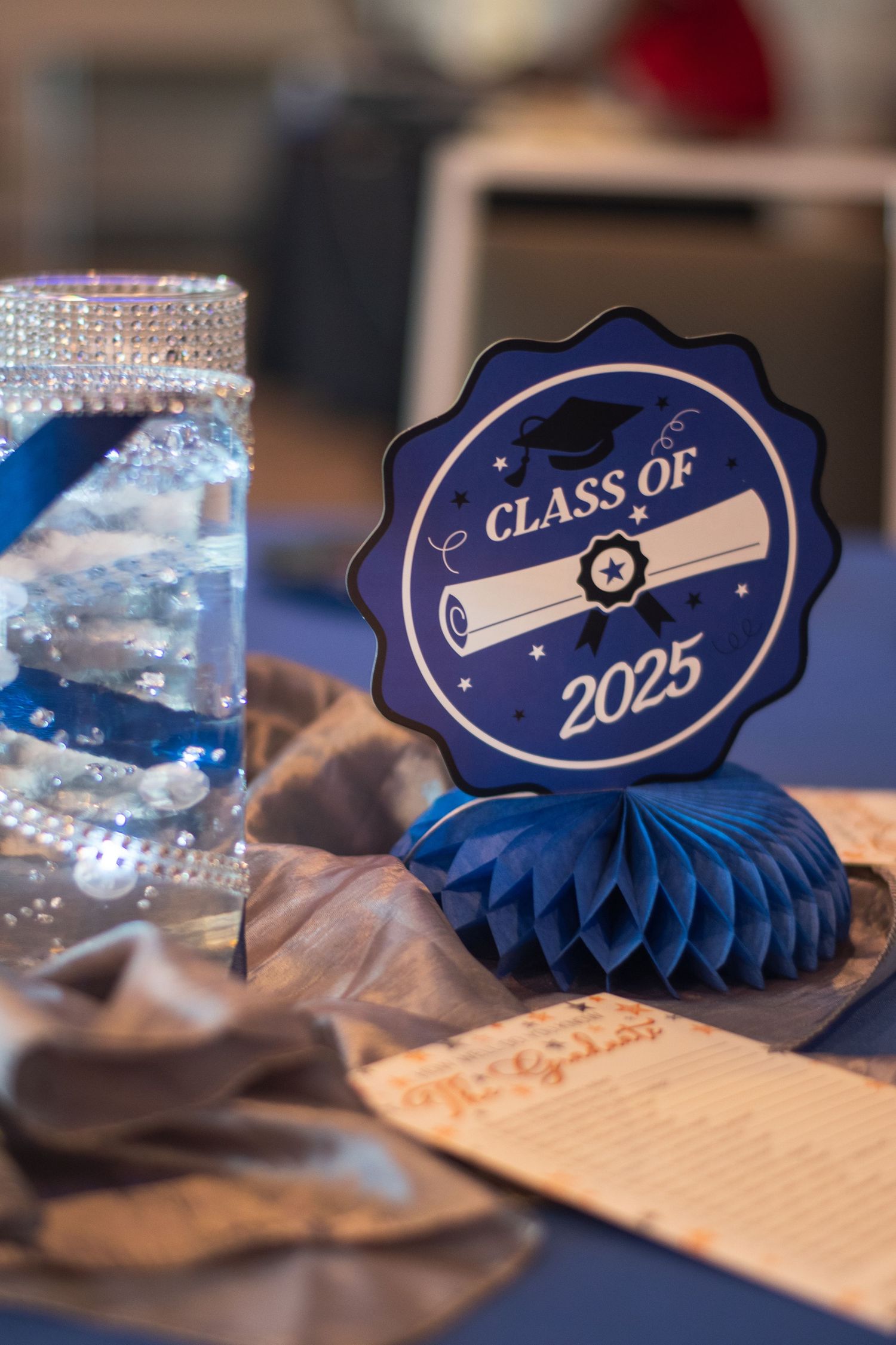 Decorative blue Class of 2023 graduation fan displays with sparkly details and diploma designs on a wooden surface.