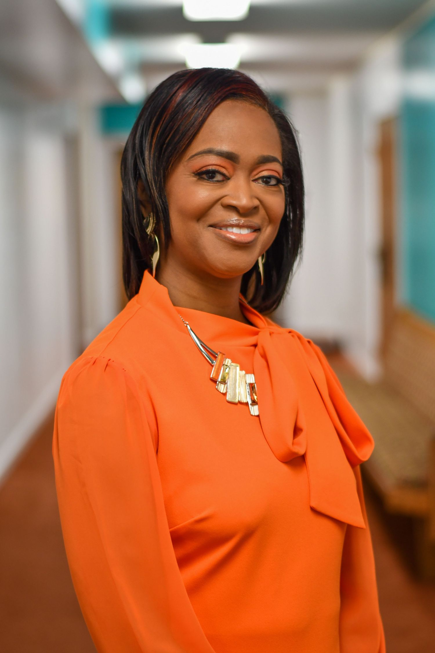 Professional portrait series featuring person in bright orange business attire against office background.