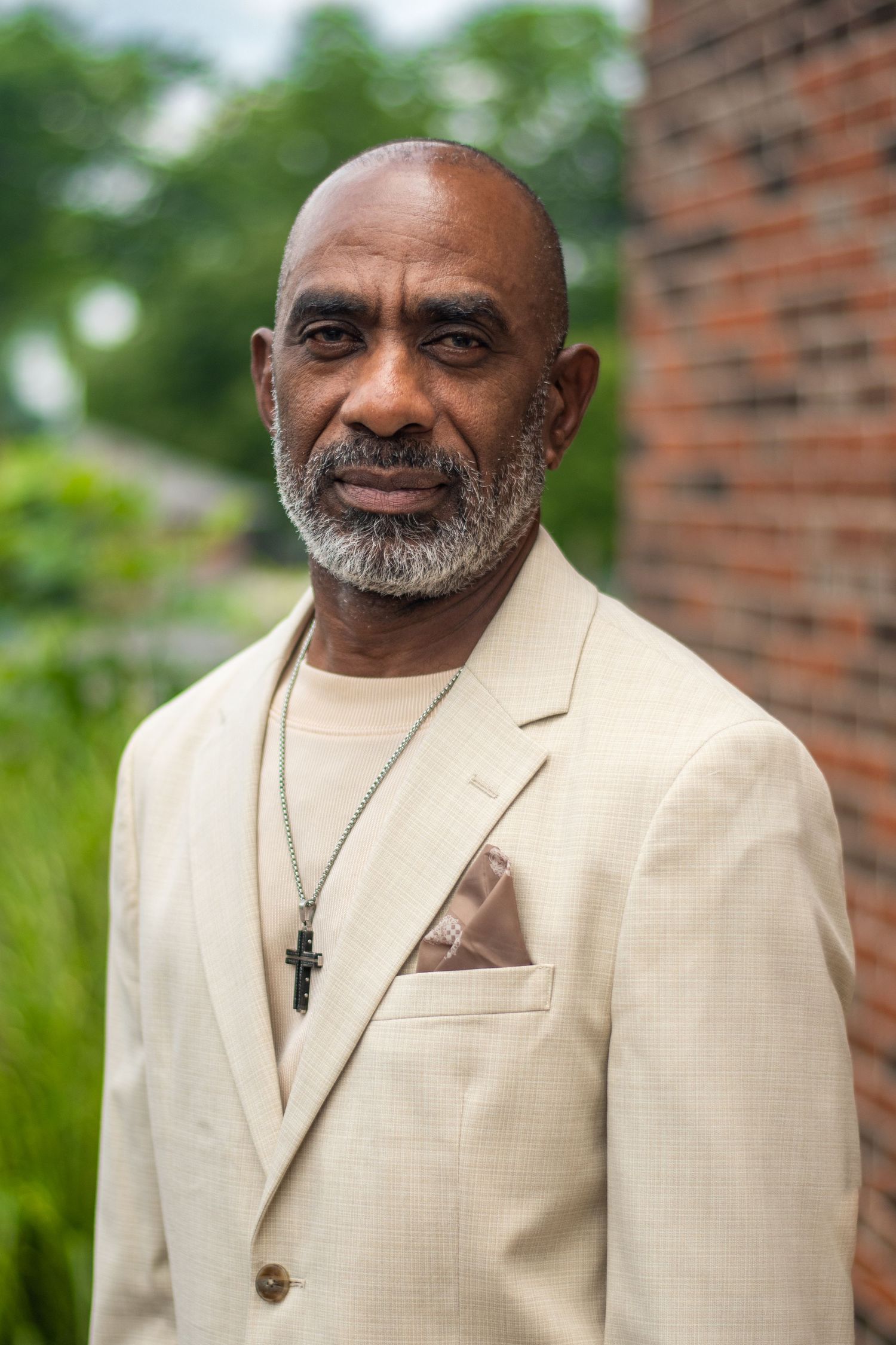 Professional headshots showing distinguished style in cream colored suit against outdoor backdrop.