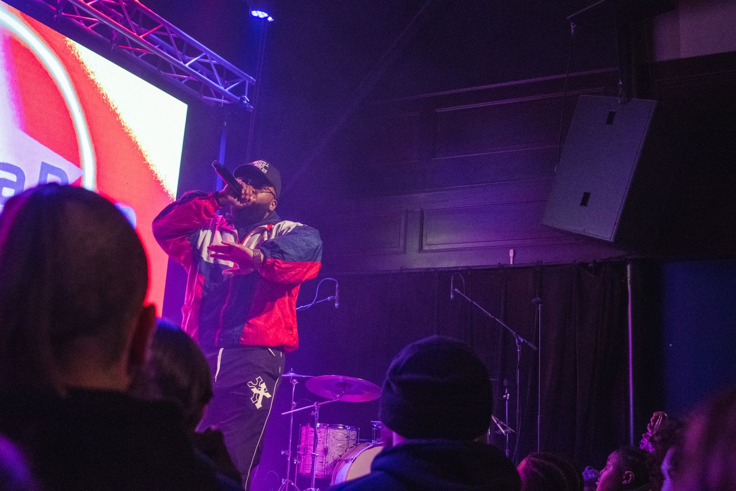 Concert performers on stage with vibrant purple and red lighting effects creating a dynamic atmosphere.