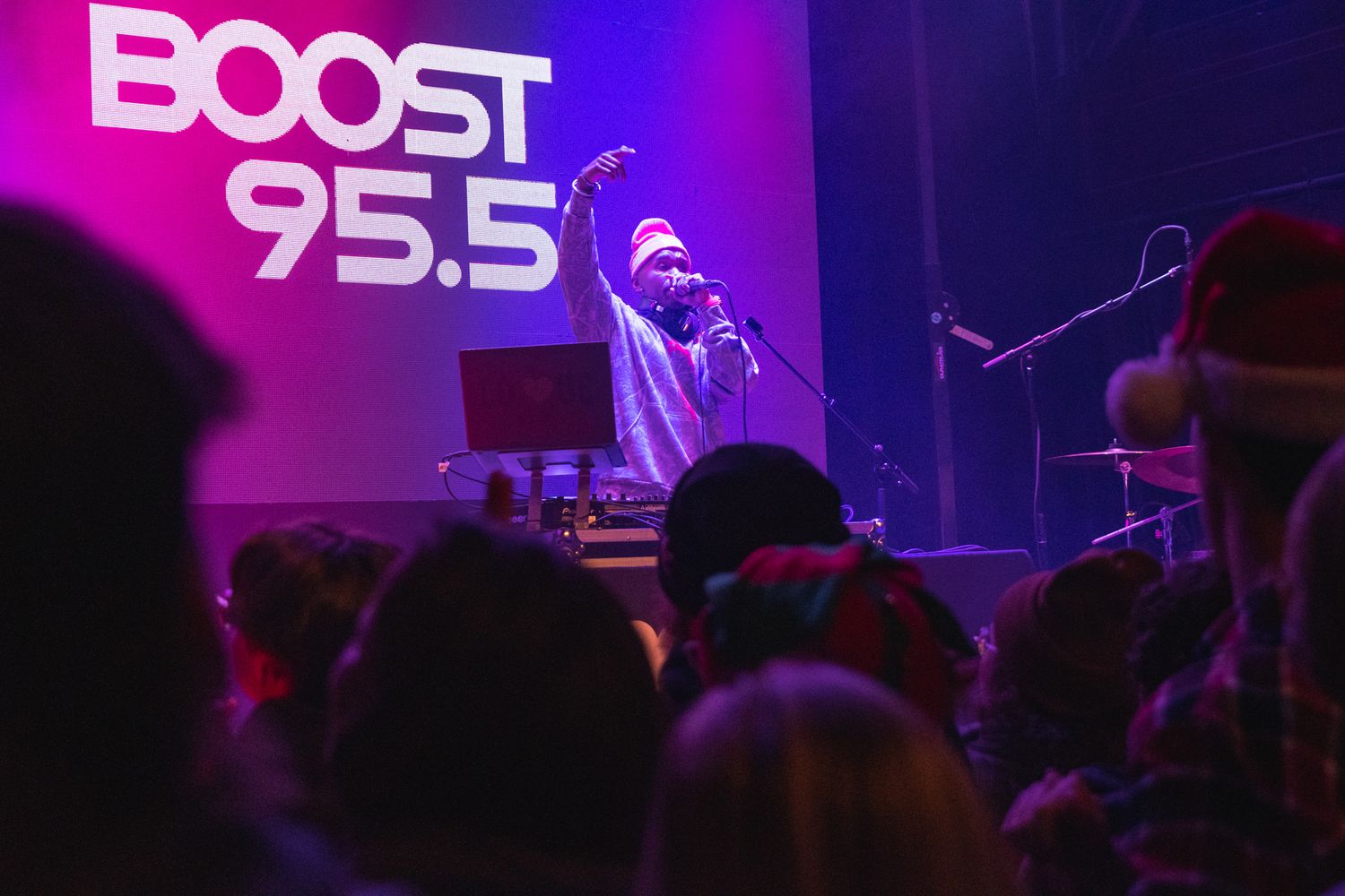 A concert crowd silhouetted against purple stage lighting at a music venue during a live performance.