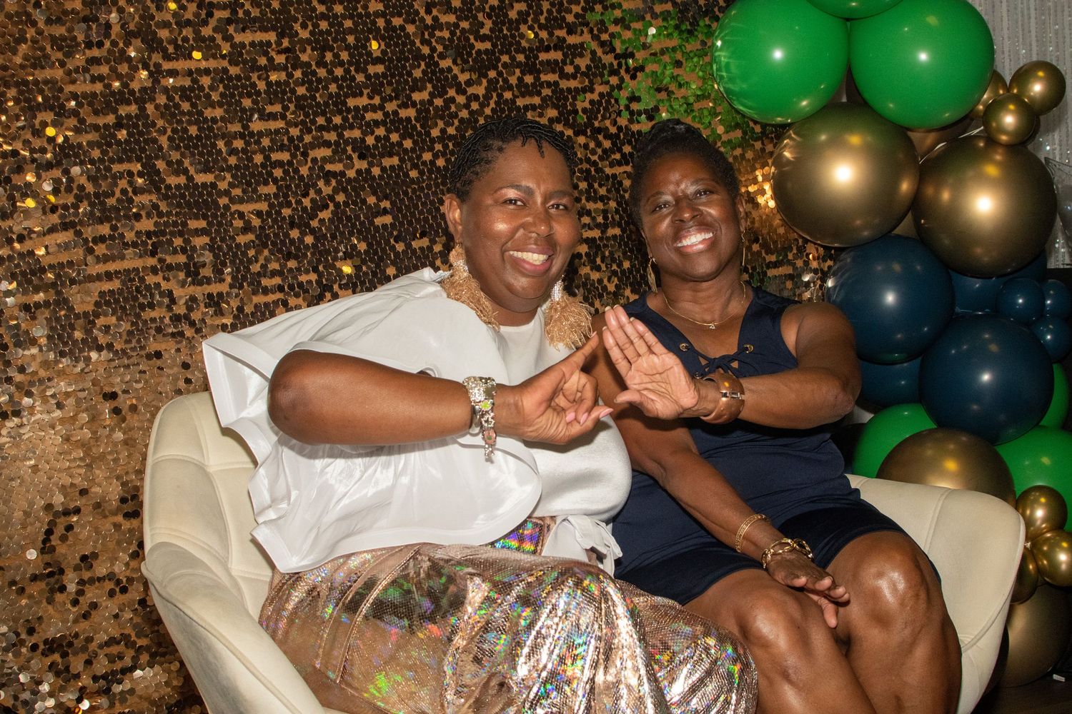 A group of friends enjoying a celebration with green and gold balloons decorating the festive party atmosphere.