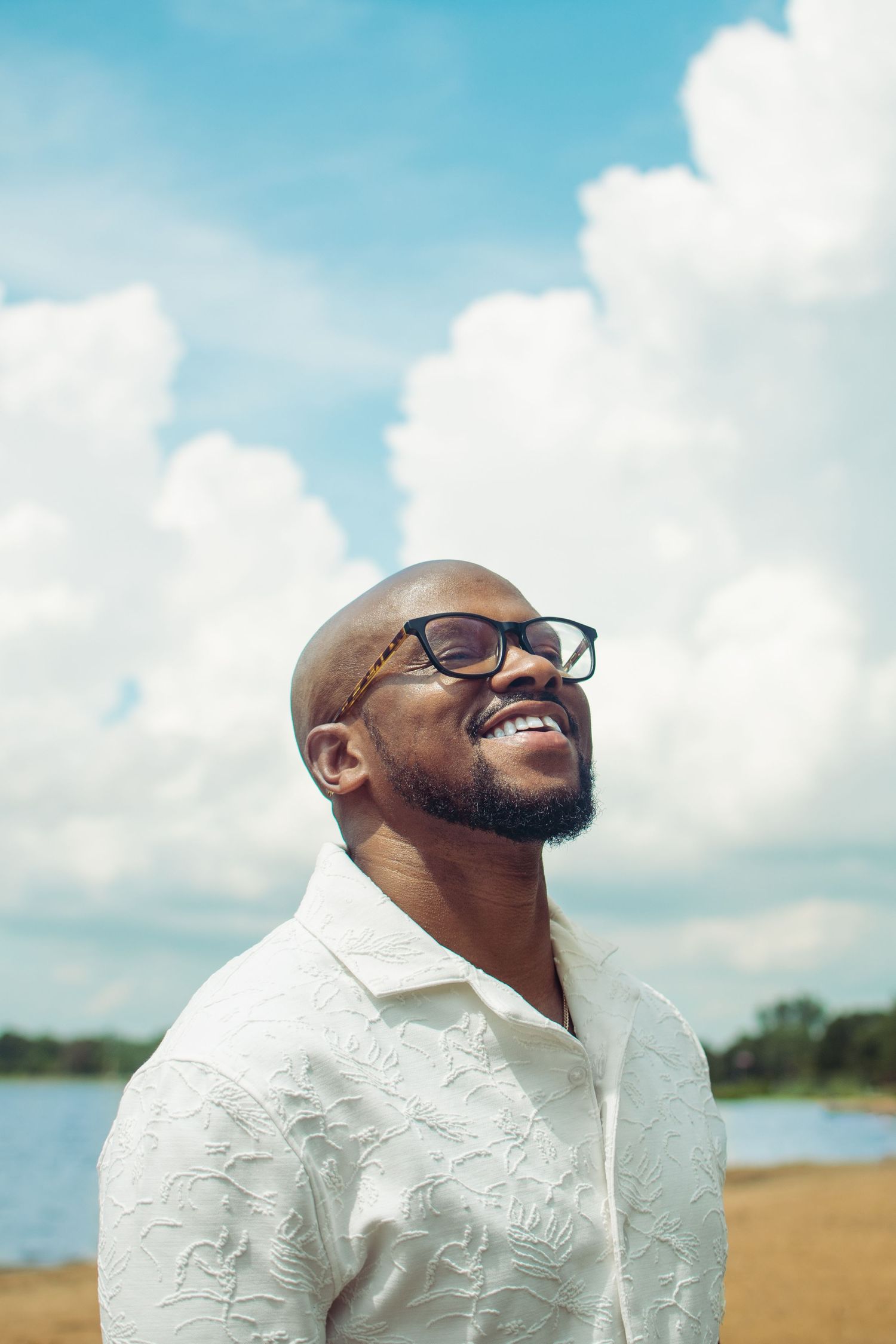 Outdoor portraits with blue sky and clouds featuring white textured shirt and glasses.