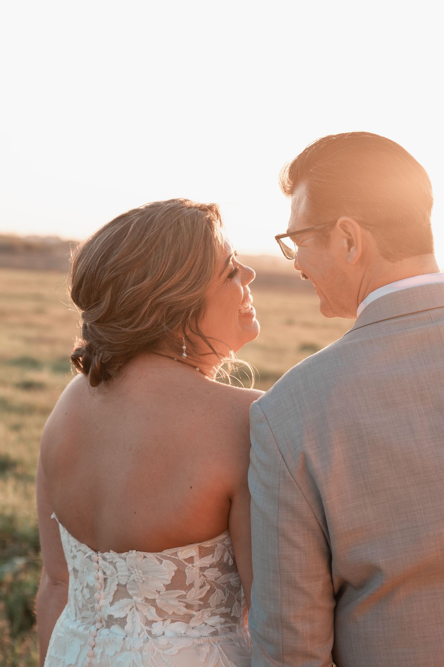 Intimate newlywed portrait of couple embracing in a dreamy open meadow