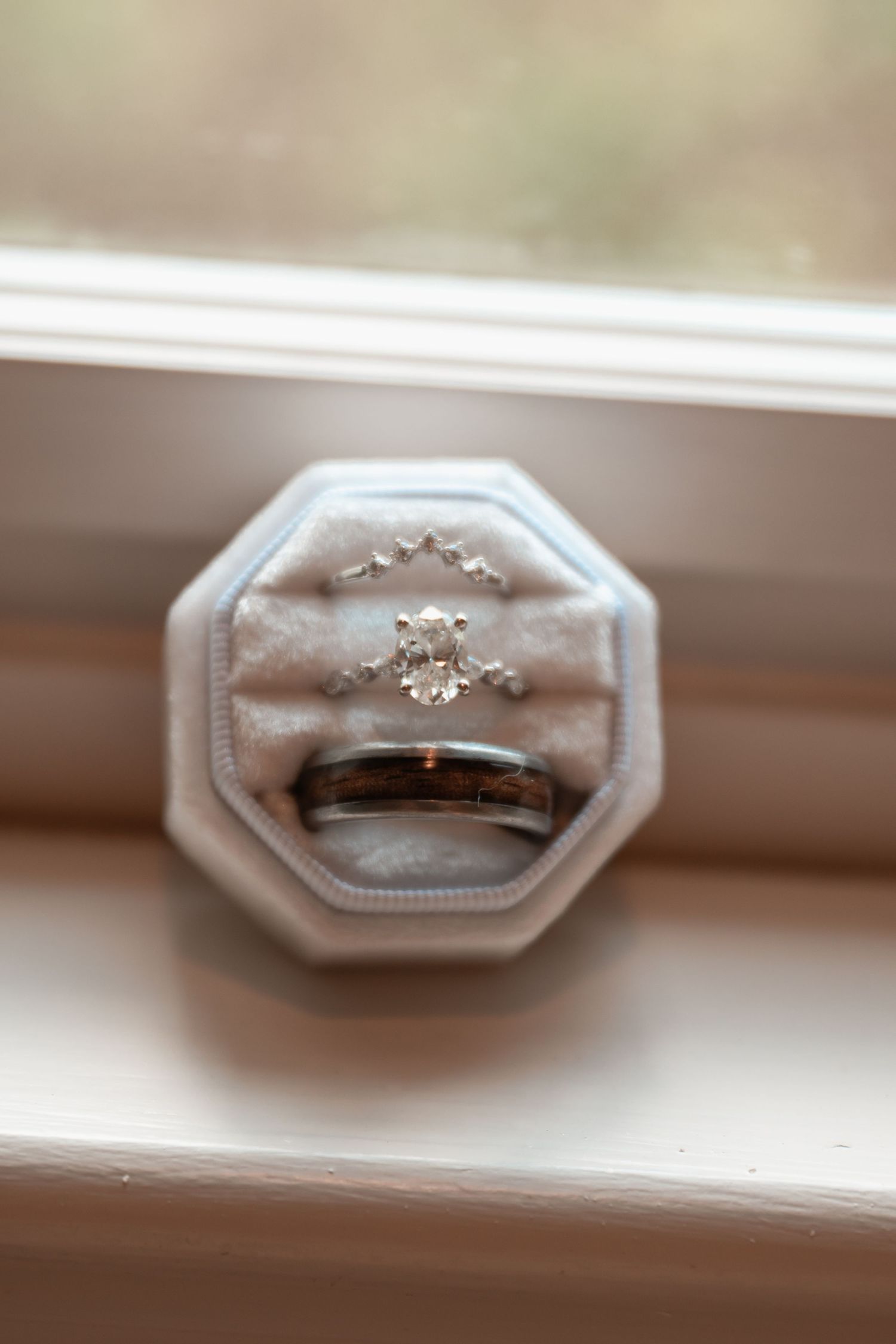 Oval diamond engagement ring with star accents and tungsten wedding band displayed in a velvet octagonal ring box.
