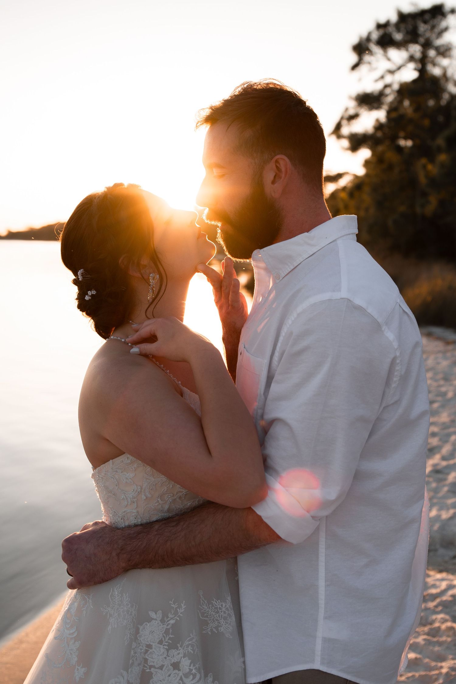 Timeless wedding portrait of couple on sandy beach under glowing sunset sky