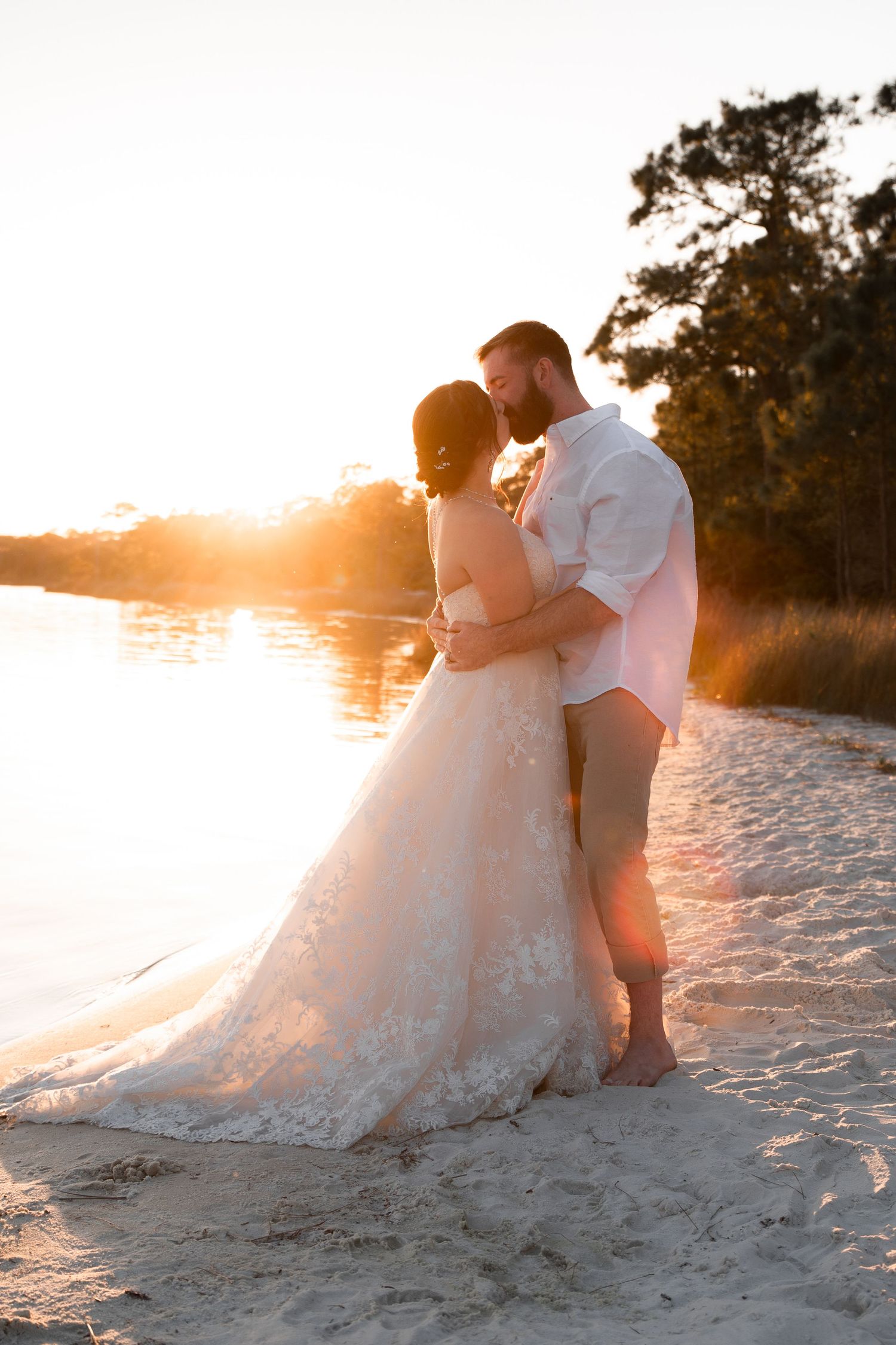 Newly married couple kissing on the beach with warm sunset tones and ocean breeze
