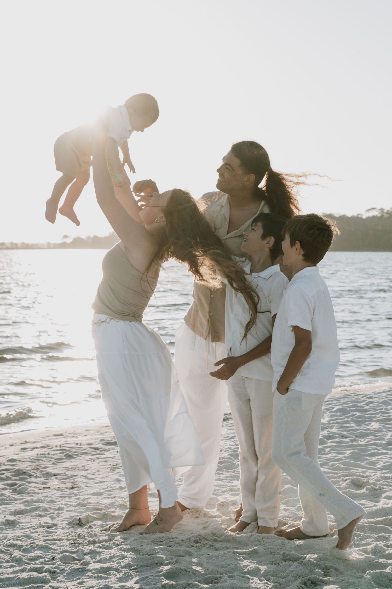 Joyful family of five playing on sandy beach during golden sunset.