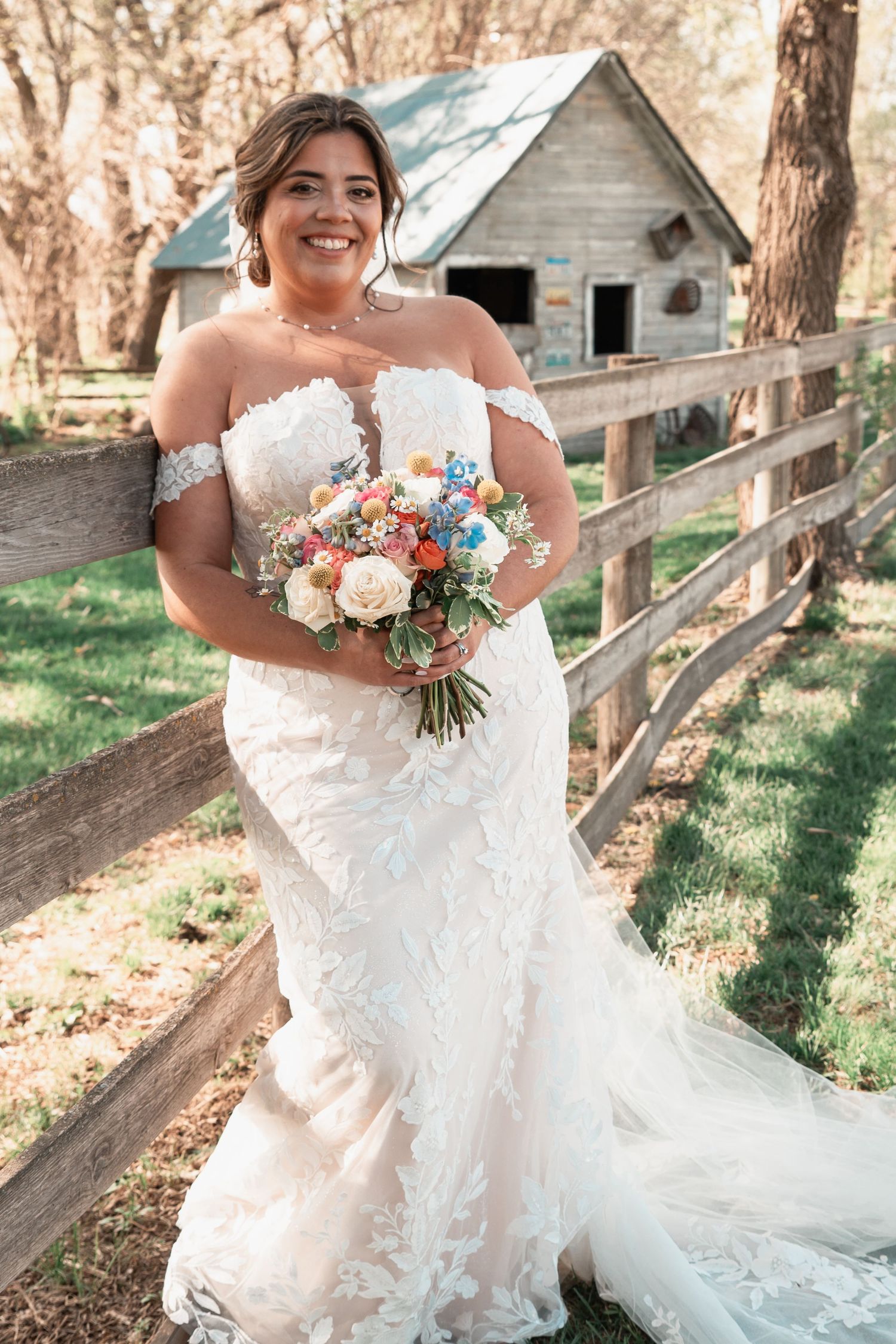 Dreamy bridal session featuring bride on weathered fence with soft sunset light