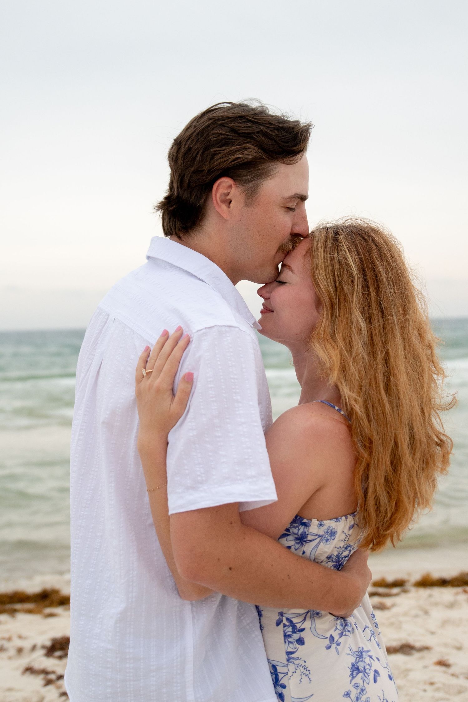 Dreamy beach proposal moment with soft sunset sky and intimate celebration